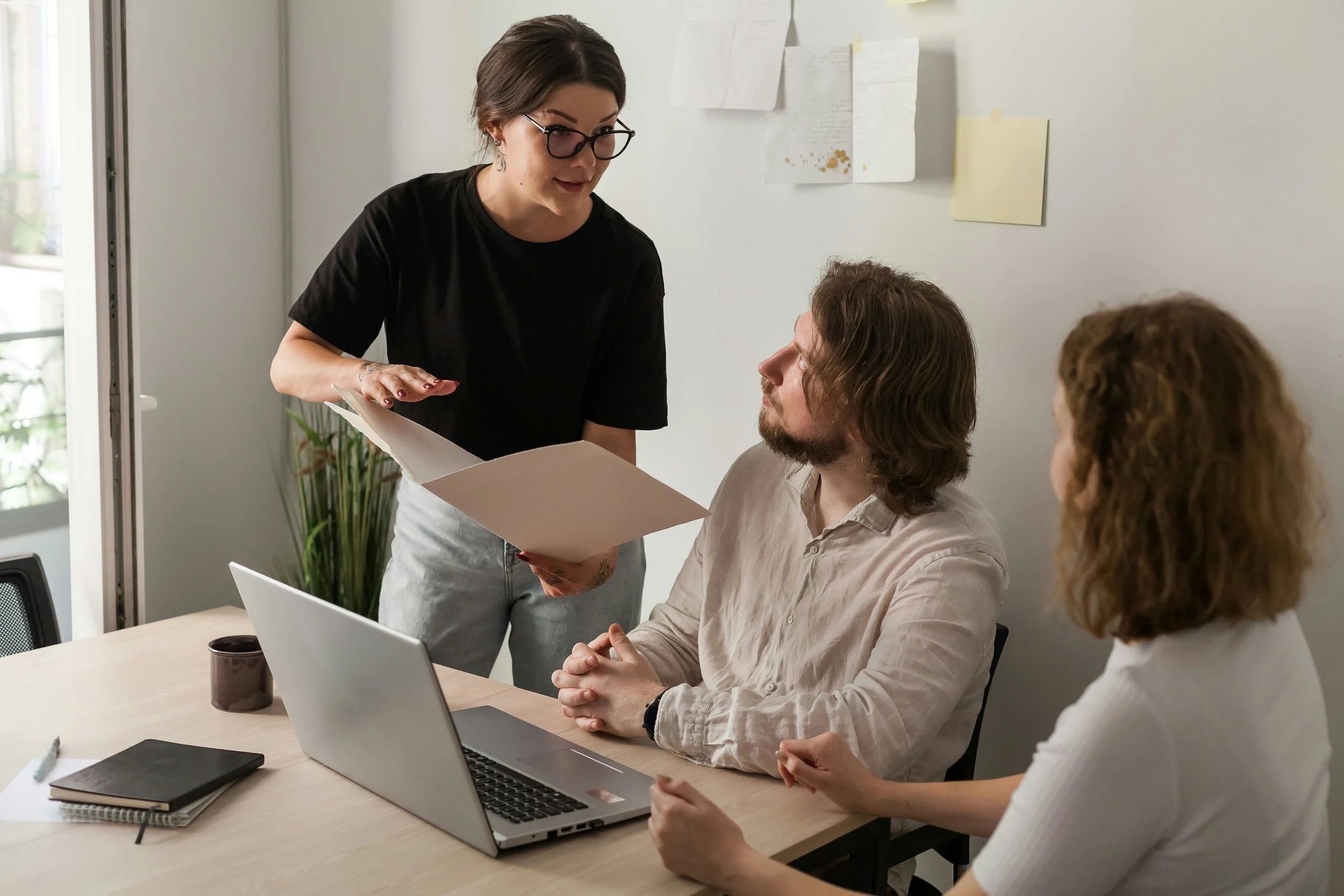 Team in discussion around a laptop representing conversation-focused leadership and collaborative decision-making