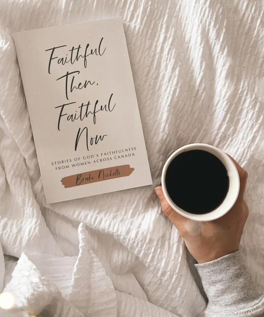 A white book titled 'Faithful Then, Faithful Now' by Brooke Nichols resting on a textured white bedspread, next to a hand holding a white mug filled with black coffee.