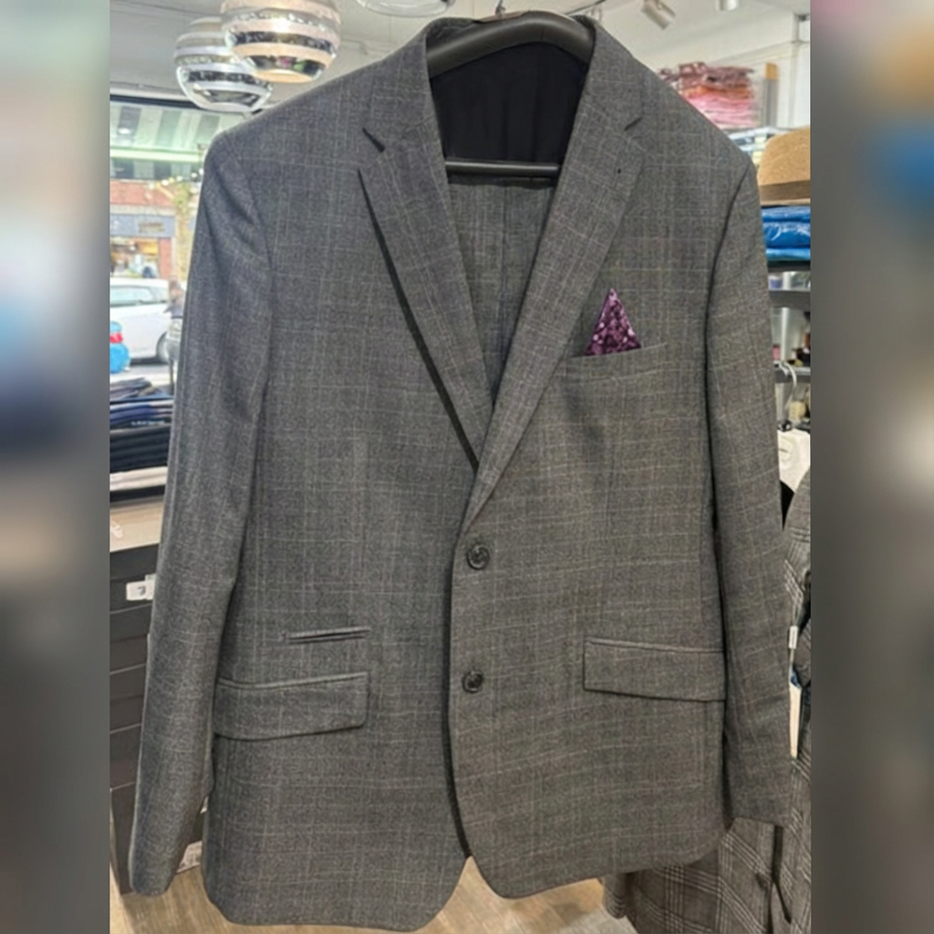 Gray checkered men's suit jacket with a purple pocket square hanging on a black hanger inside a store.