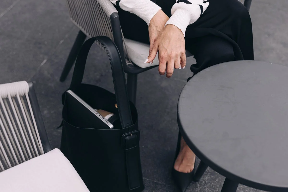 close shot of professional woman sitting in chair with laptop bag next to her