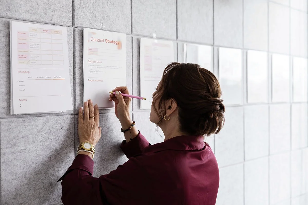 woman brainstorming social media content plan by writing on documents pinned to wall