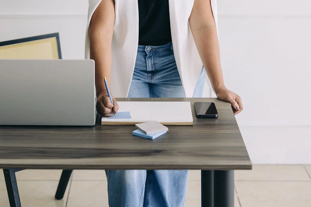 woman business owner standing at desk, writing on notepad and working on brand clarity