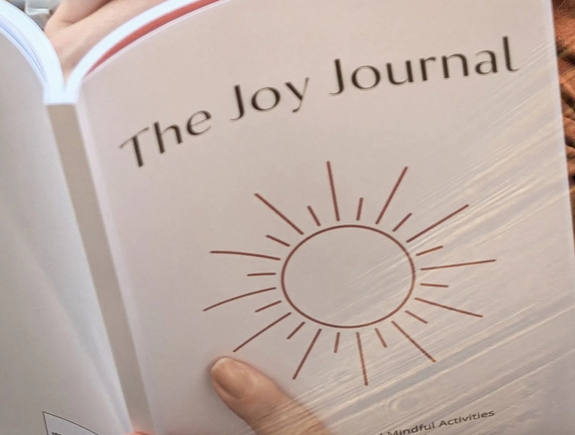 Open book titled "The Joy Journal" with a sun illustration on the cover.