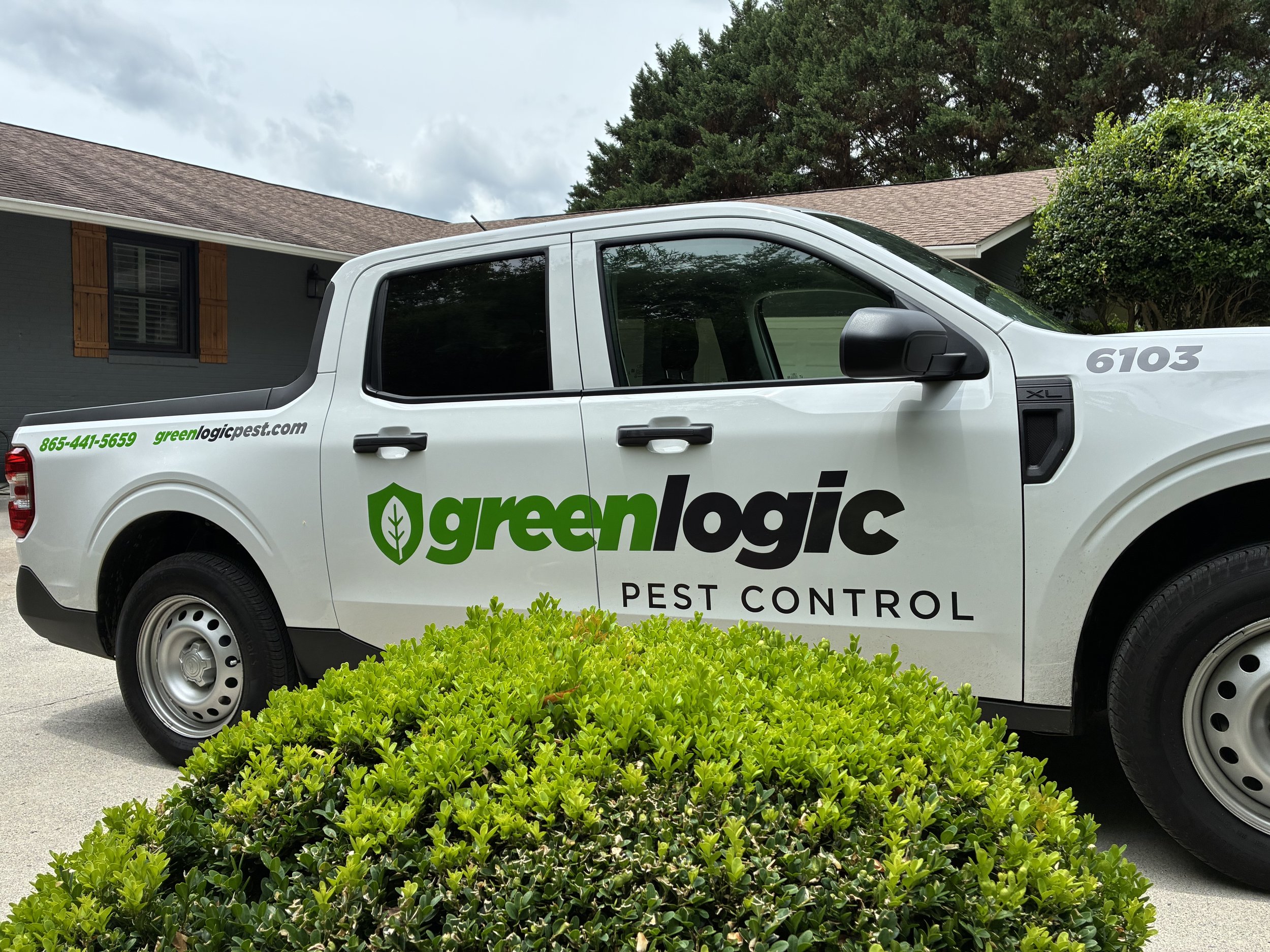 Greenlogic Pest Control Service Truck in front of greenery at customer's home