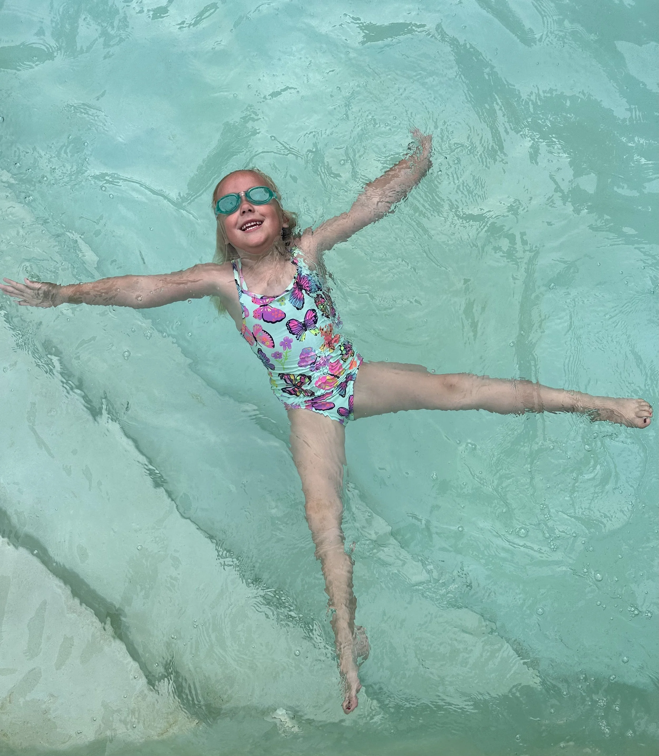 ISR program. Infant swimming resource.A young child is happily using her survival swim skills to self-rescue independently in a swimming pool. She is smiling and confident in her ability to perform her survival swim skills.
