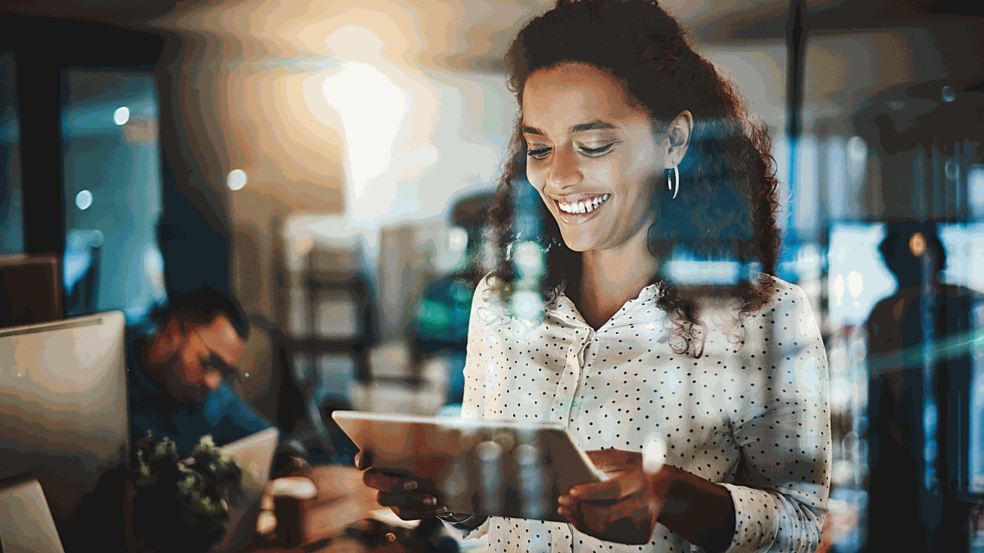 Smiling woman looking at a tablet in a busy cafe or restaurant.