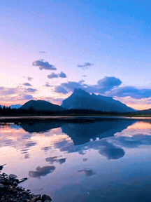 Scenic view of a mountain reflected in a calm lake during sunset or sunrise.