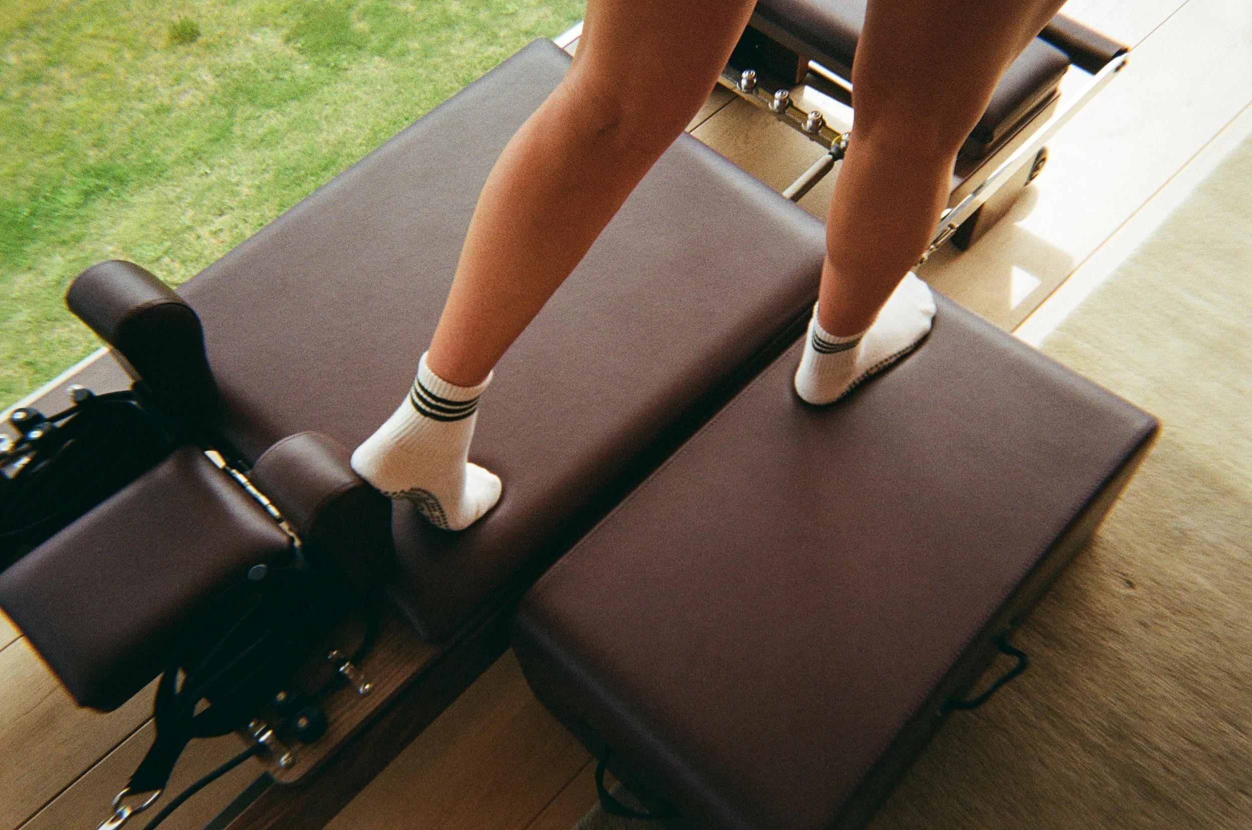 Person standing on a massage table wearing black and white striped socks, with a green outdoor area visible outside.