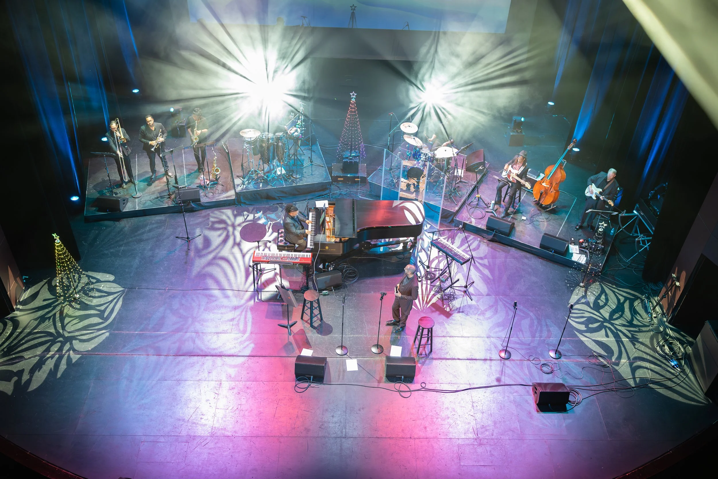Live music performance on a professional theatre stage with full band and production lighting.