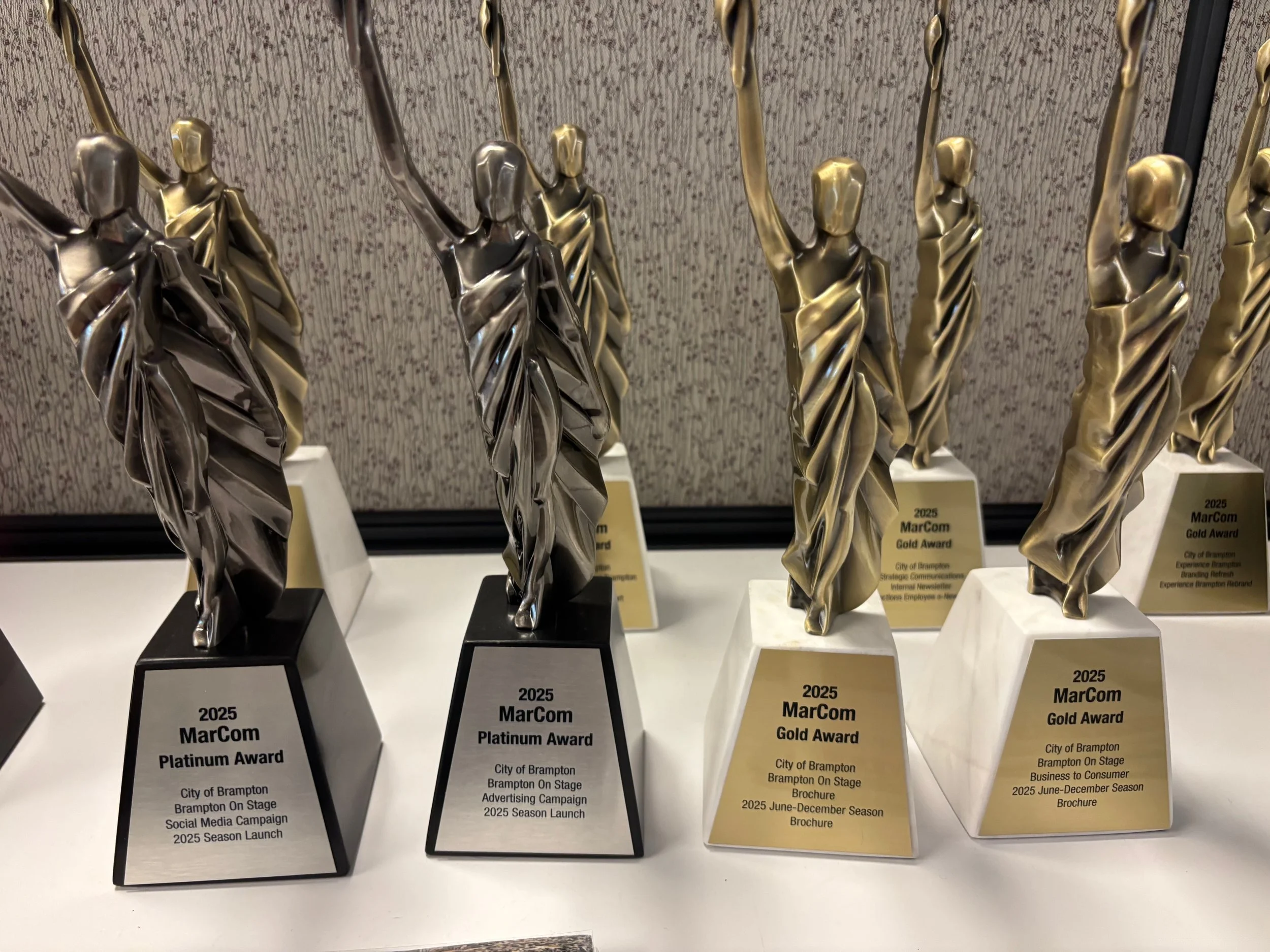 Multiple 2025 MarCom Platinum and Gold Awards for City of Brampton’s Brampton On Stage campaigns displayed on a table.