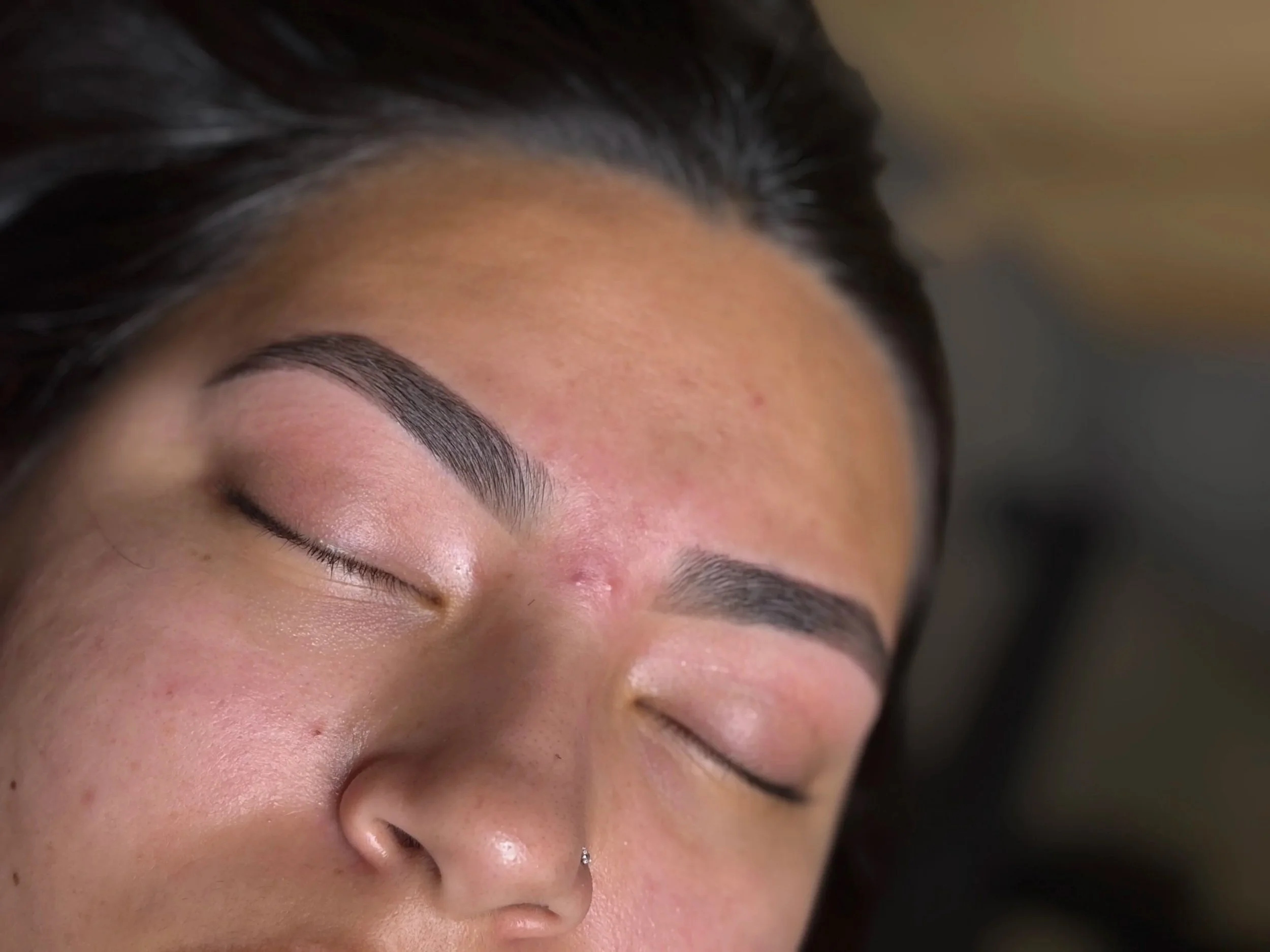 Close-up of a woman's face with closed eyes, showing well-groomed eyebrows, freshly waxed brows.