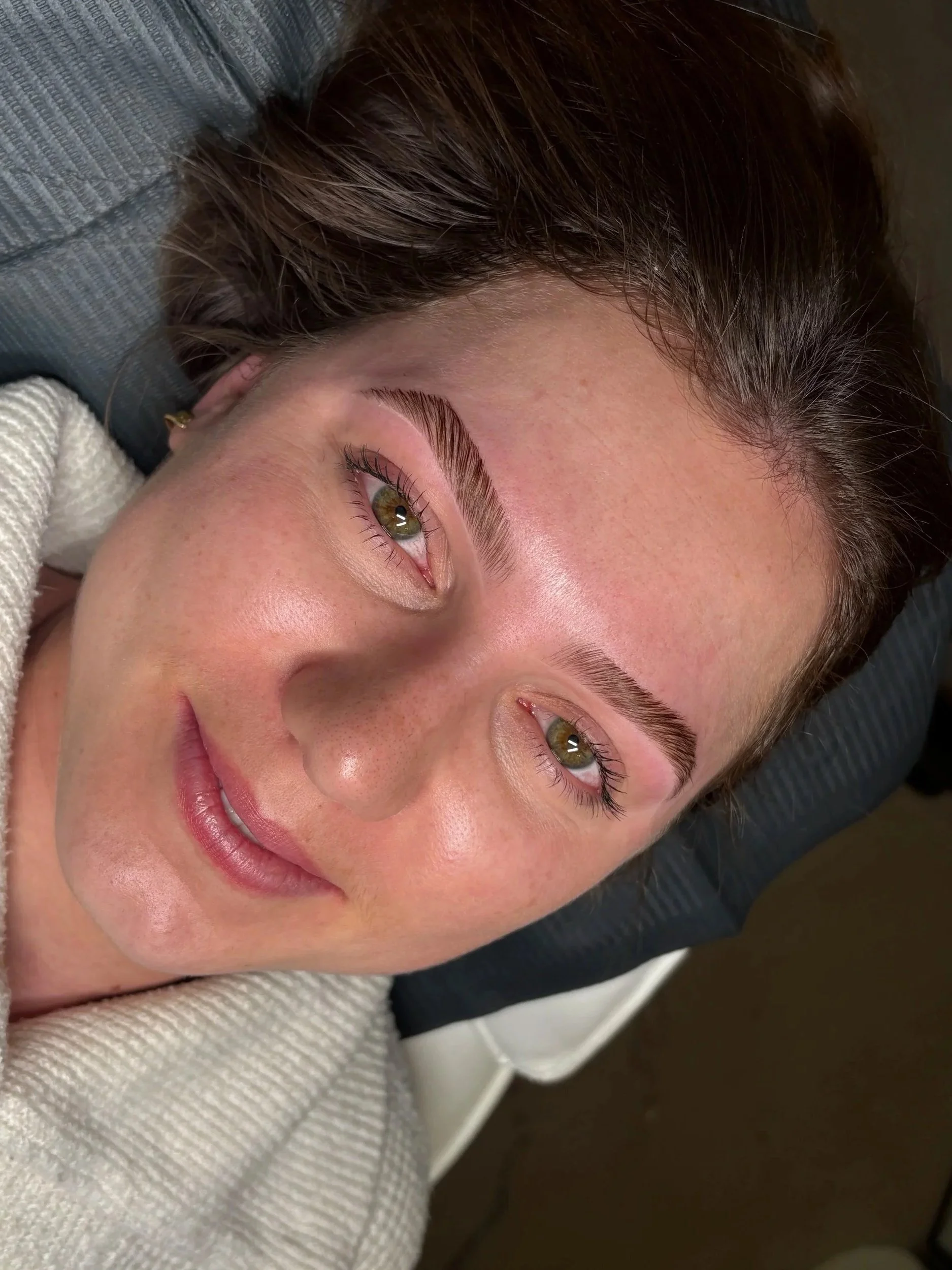 Close-up of a smiling woman with laminated eyebrows.