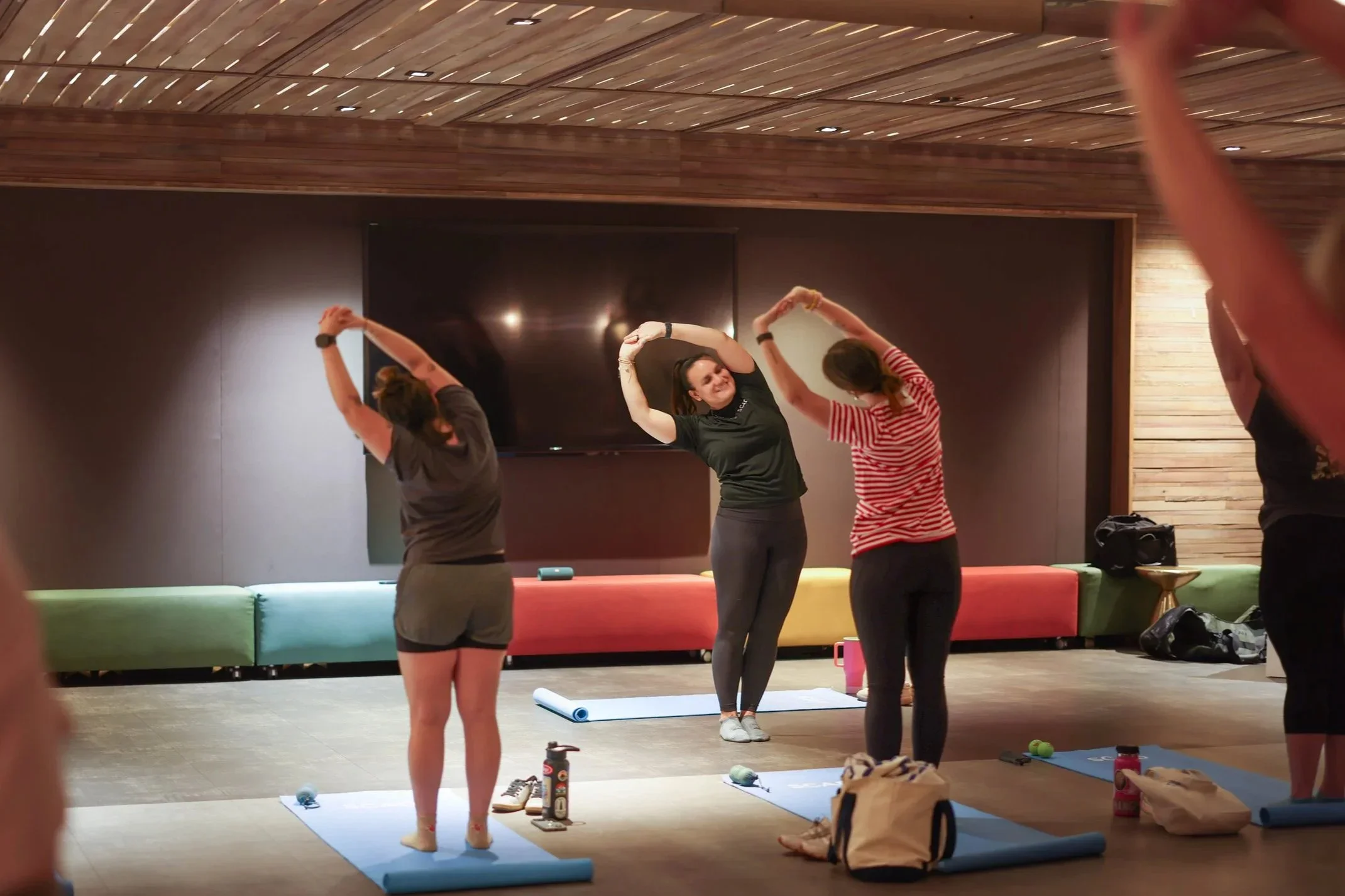 Person working on a laptop at a desk by a window, analyzing a financial report displayed on the screen. The desk has a calculator, papers, a plant, and a checkered mug. The setting is bright with natural light.