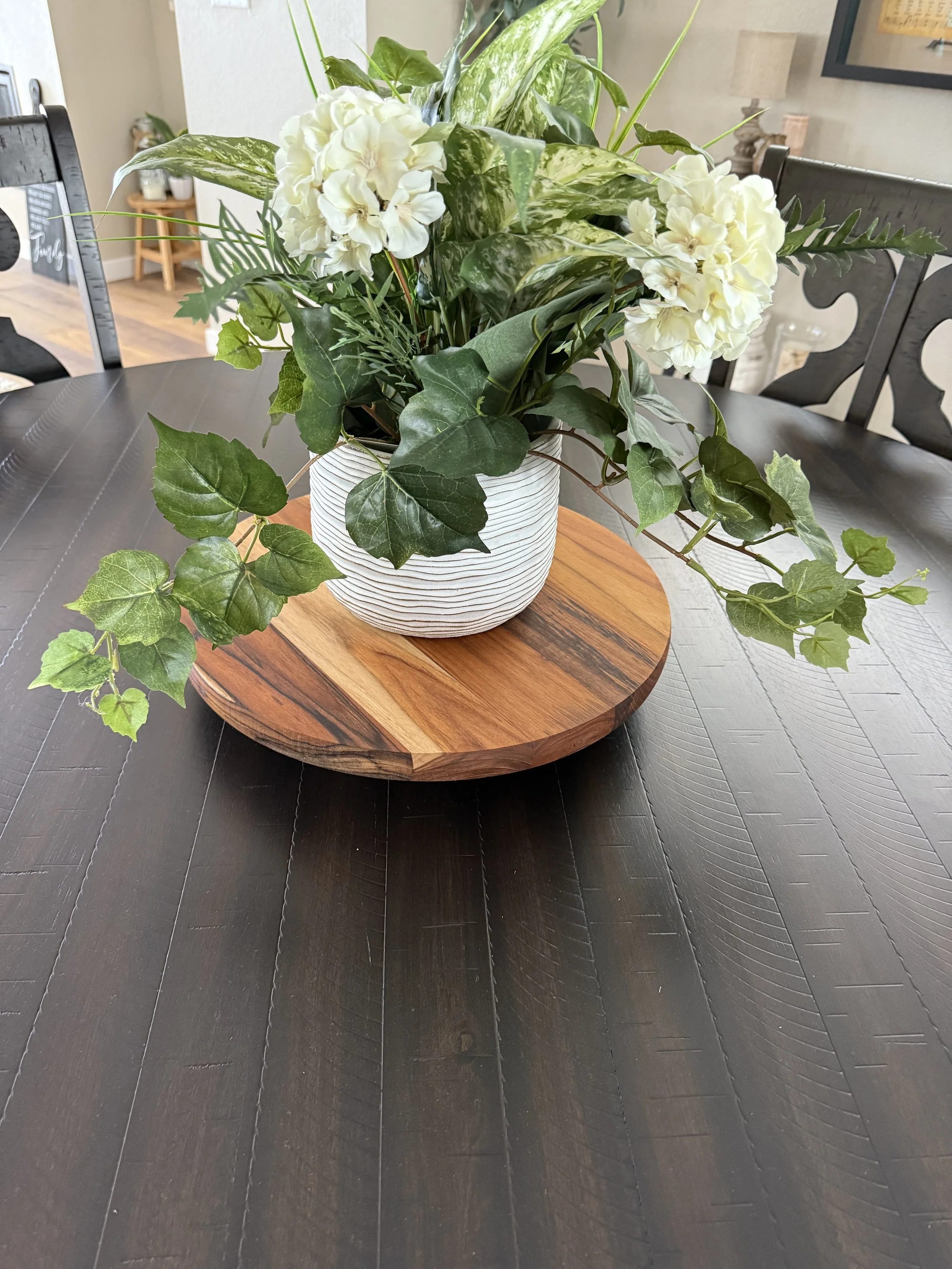 Handcrafted round wooden centerpiece board with natural wood grain, styled with a floral arrangement.