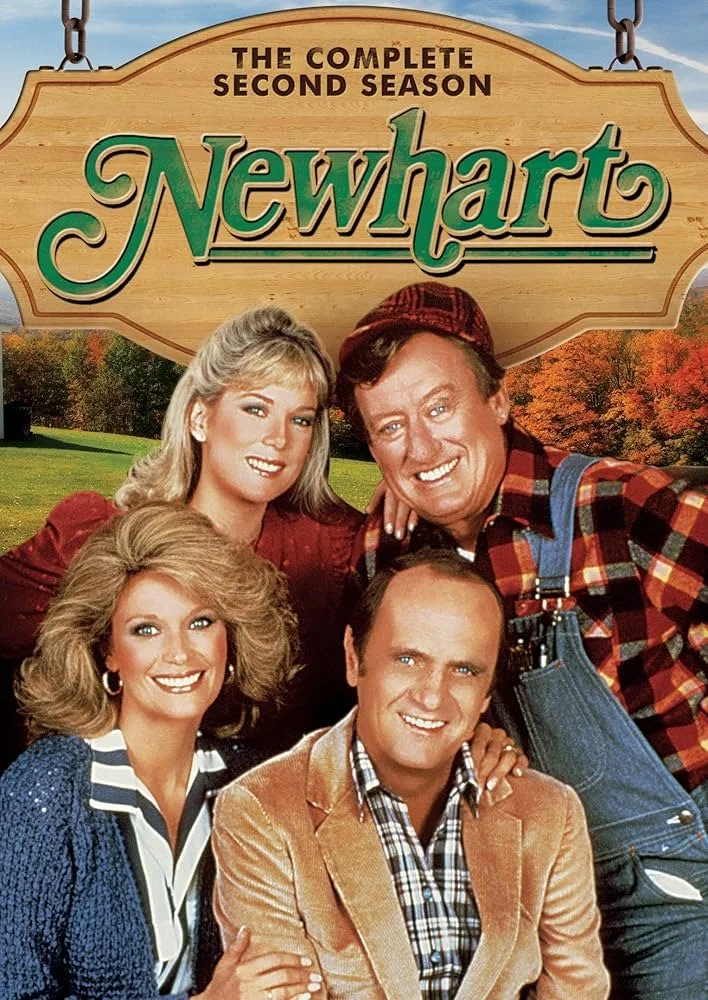 Promotional poster for the TV show Newhart, featuring four main characters outdoors against a background of trees with fall foliage. The four individuals are smiling, with one sitting in the front, two standing behind, and one leaning over the person in front. The show is labeled as 'The Complete Second Season' at the top.