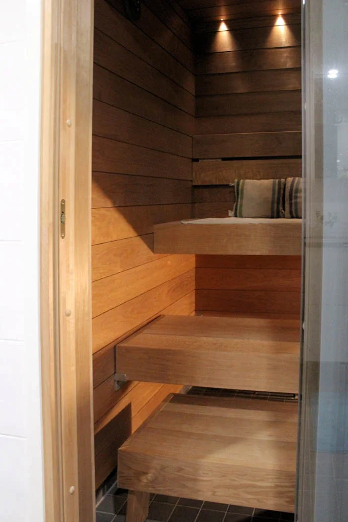 Sauna, jossa vaalea vaakapaneeli, seinät ja penkit on tehty samanvärisestä puusta.