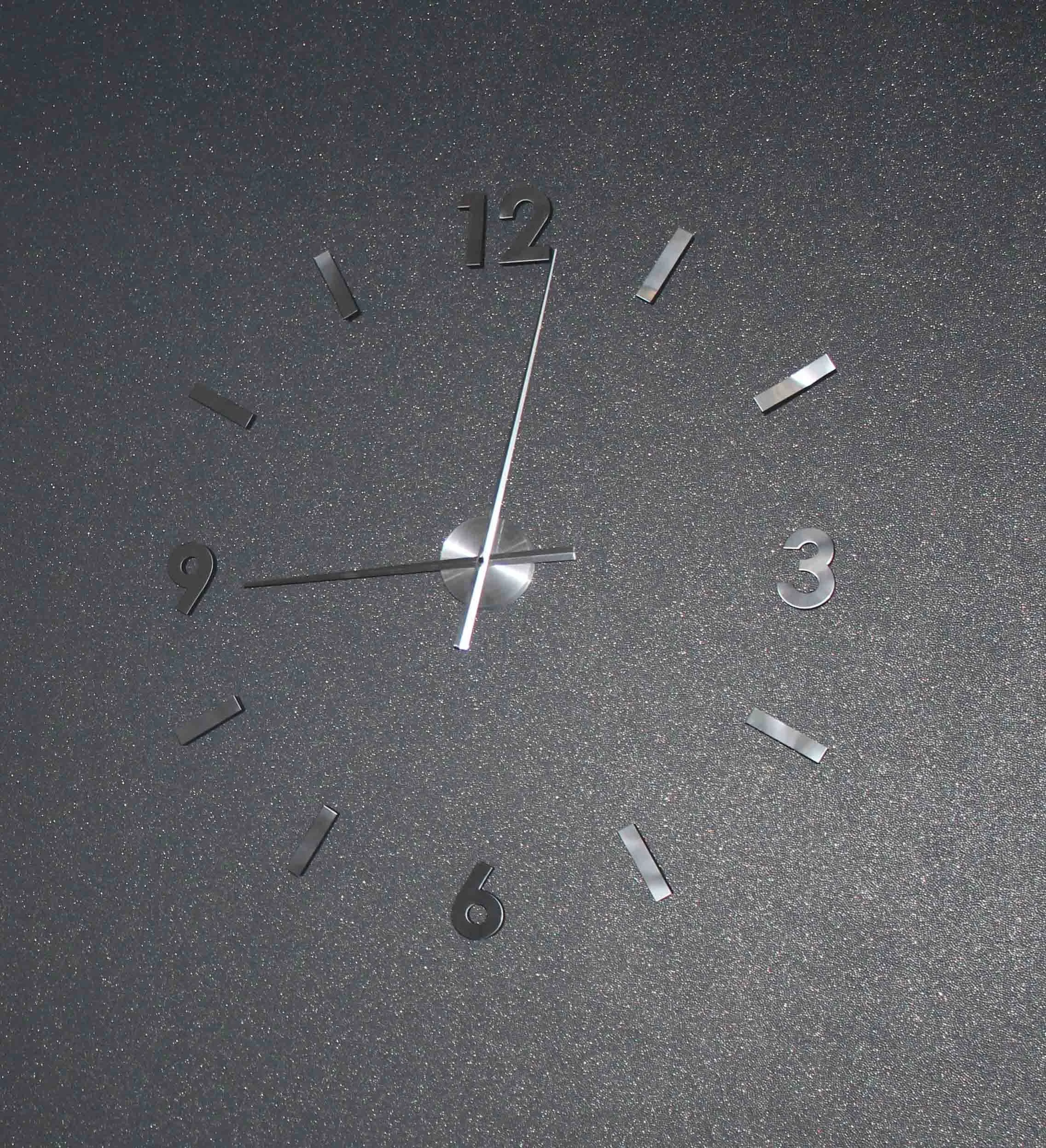 Kellotaulu näyttää ajan 12:03, taustassa tummalla taustalla paljon pieniä kirkkaita pisteitä, jotka muistuttavat tähtitaivasta.