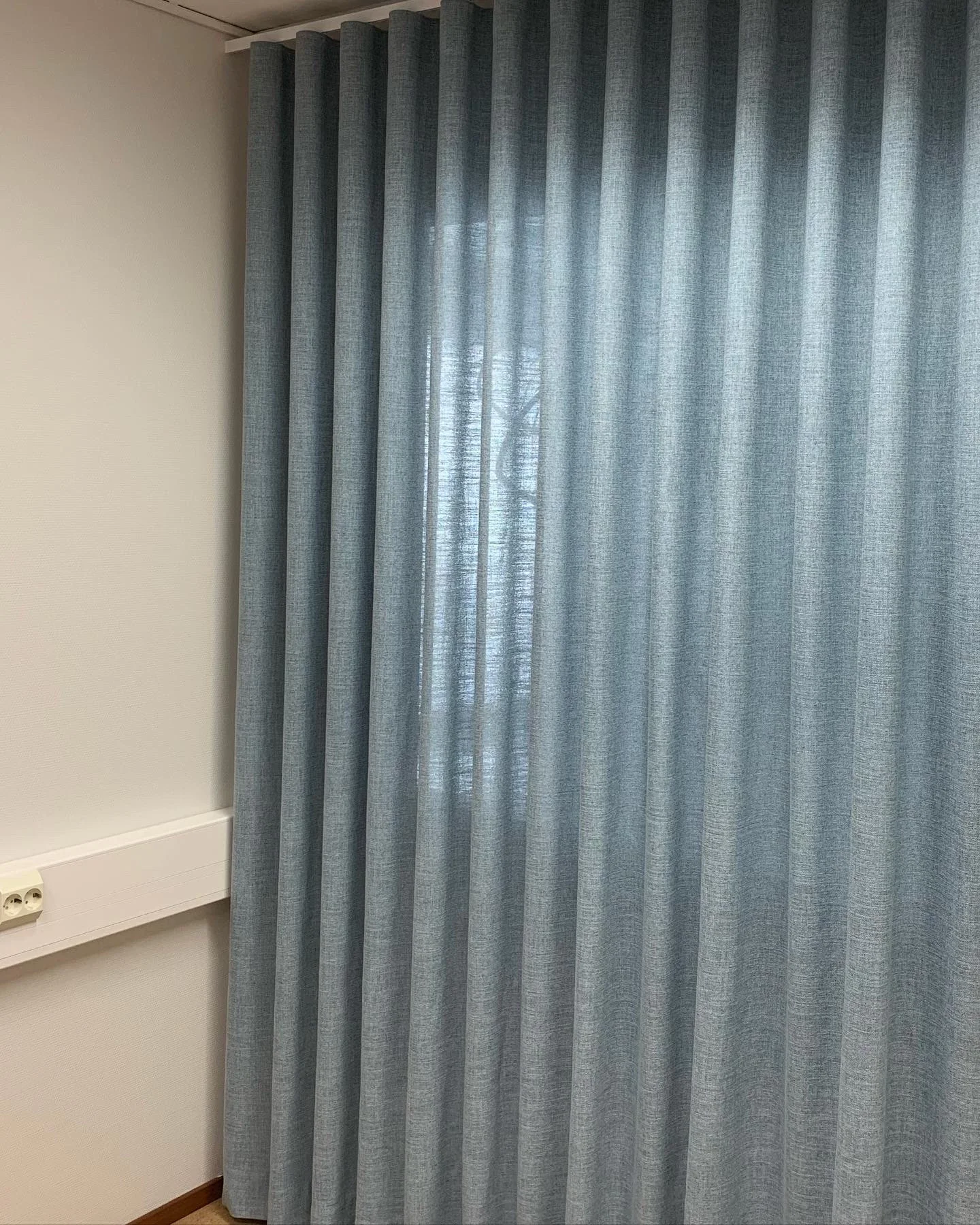 Sininen verho peittää ikkunan huoneessa.