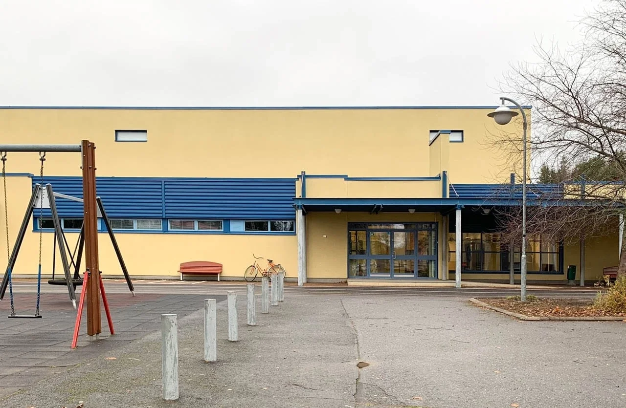 Urheilutalo ulkon, leikkialue ja puut, talvi, pilvinen sää.
