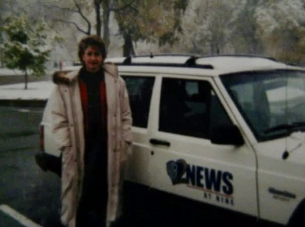 Julie standing next to a news vehicle in an outdoor setting.
