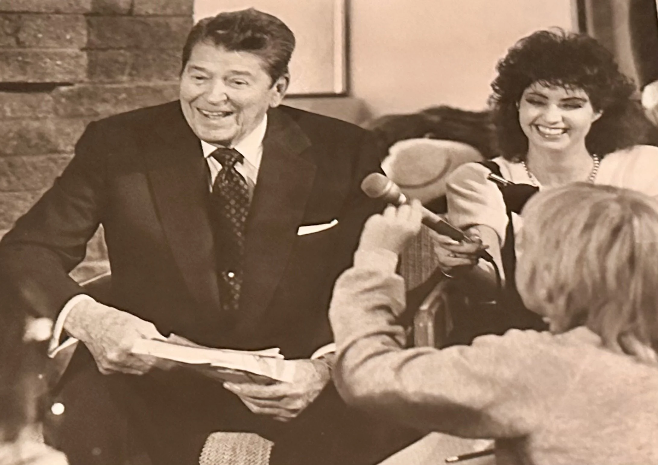 Ronald Regan and Julie smiling, sitting at a table during an interview.