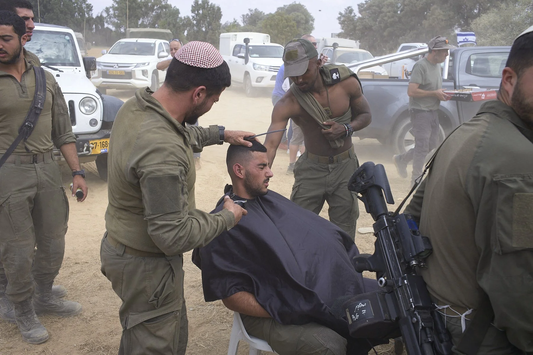 OFAKIM, ISRAEL, OCTOBER 16, 2023. October 7 Attacks aftermath. A soldier getting a haircut while meals are provided by civilians near the Gaza border.