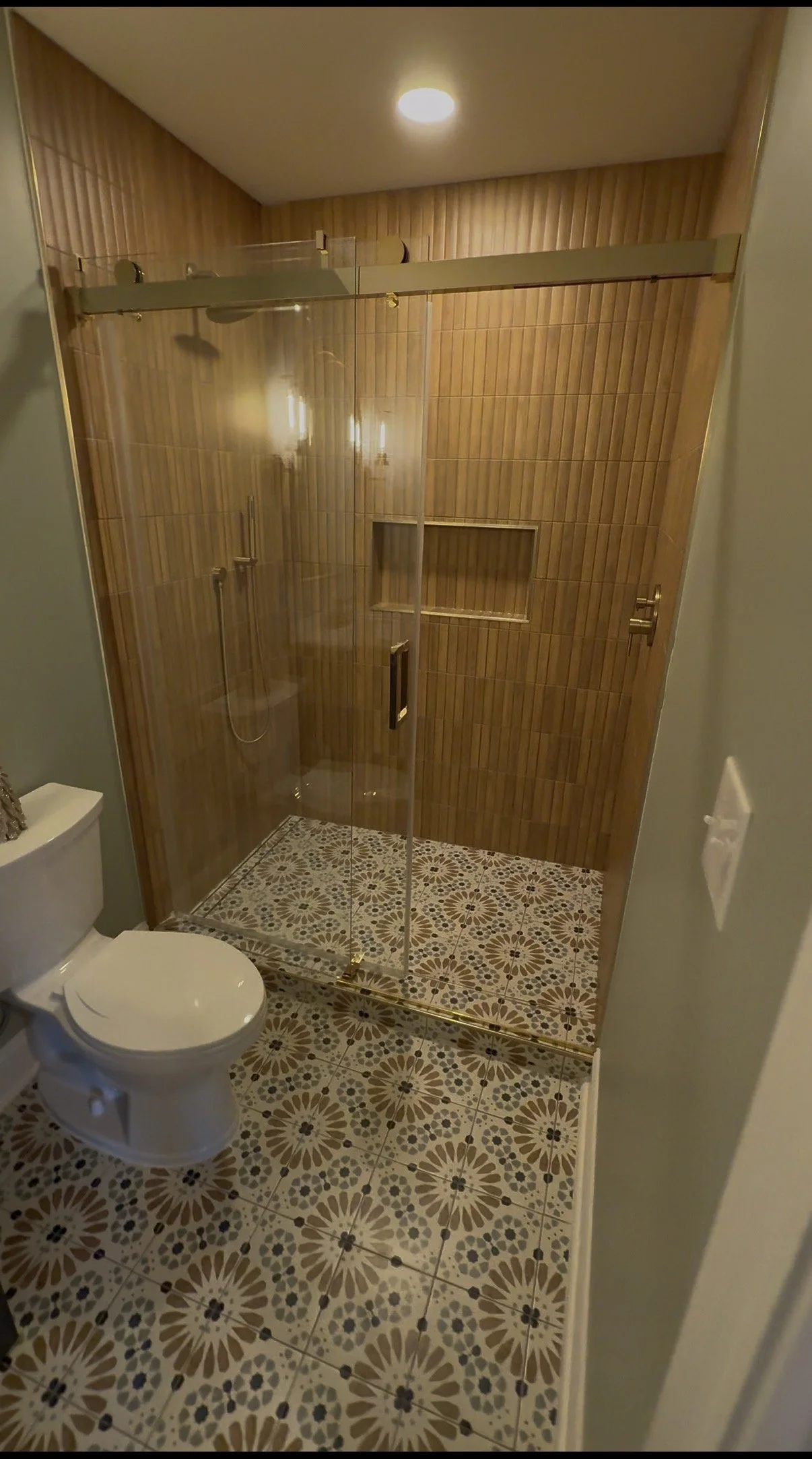 Bathroom with a glass shower enclosure, patterned floor tiles, and a toilet.