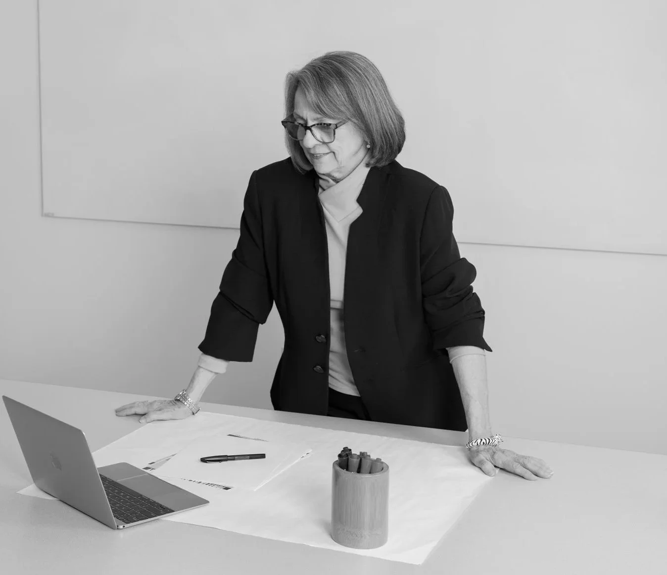 Sunnee D. O’Rork at a table with a laptop and documents, mid-work in a black-and-white portrait.