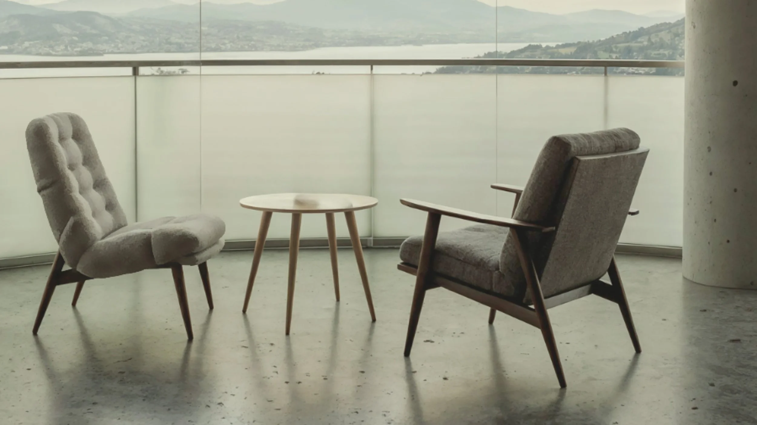 Two mid-century chairs facing a small table in a quiet, light-filled space.