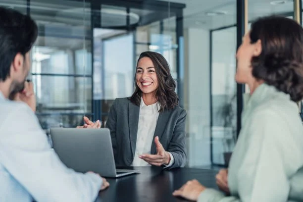Woman leading a discussion at a table with a laptop