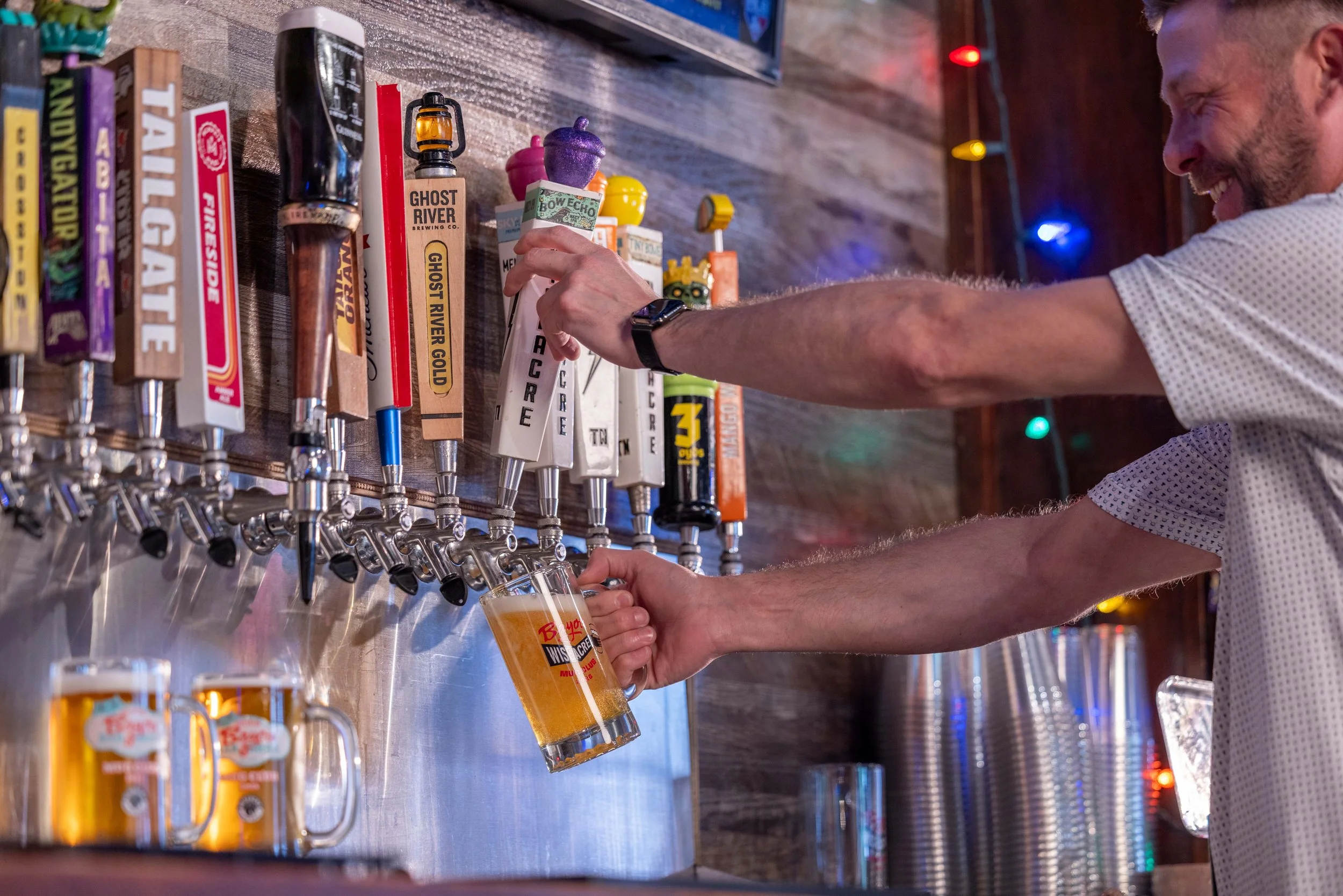 Man pouring beer into glass from draft handle.
