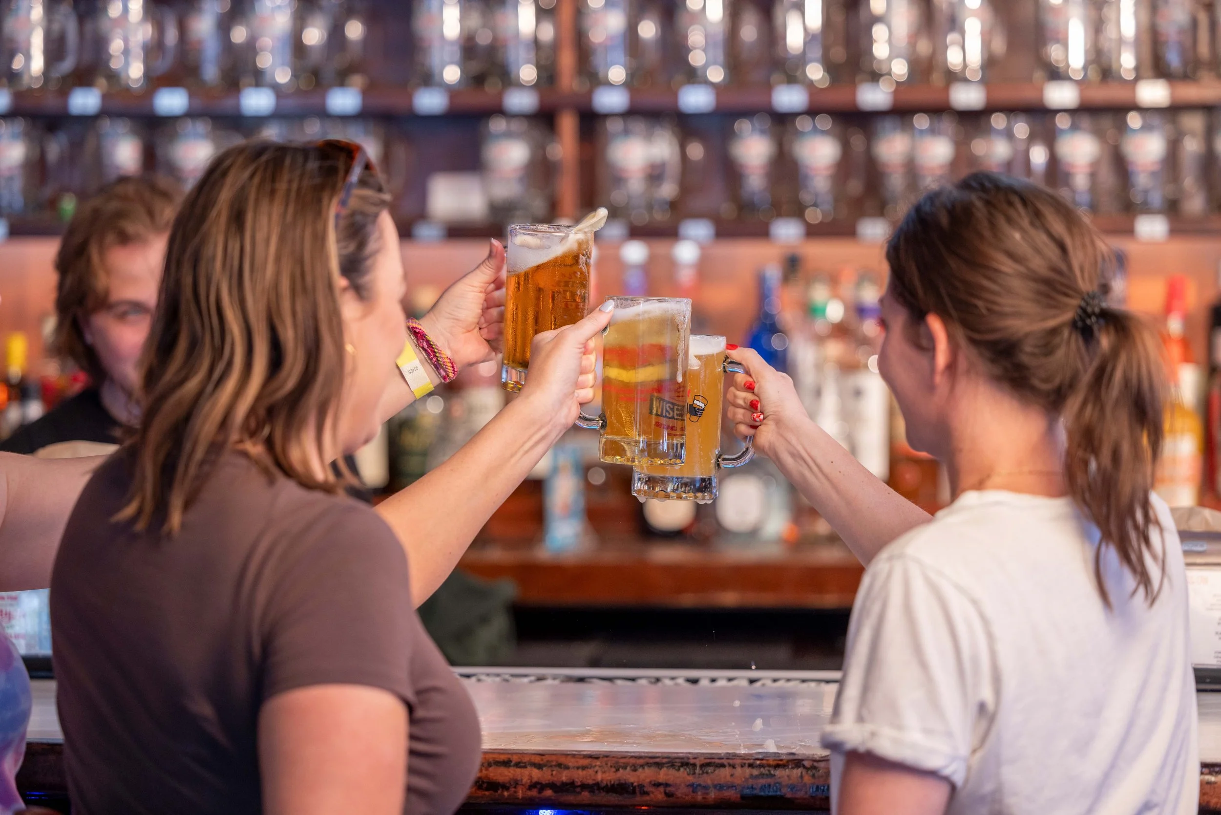 Two women smiling and clinking their beer steins together.