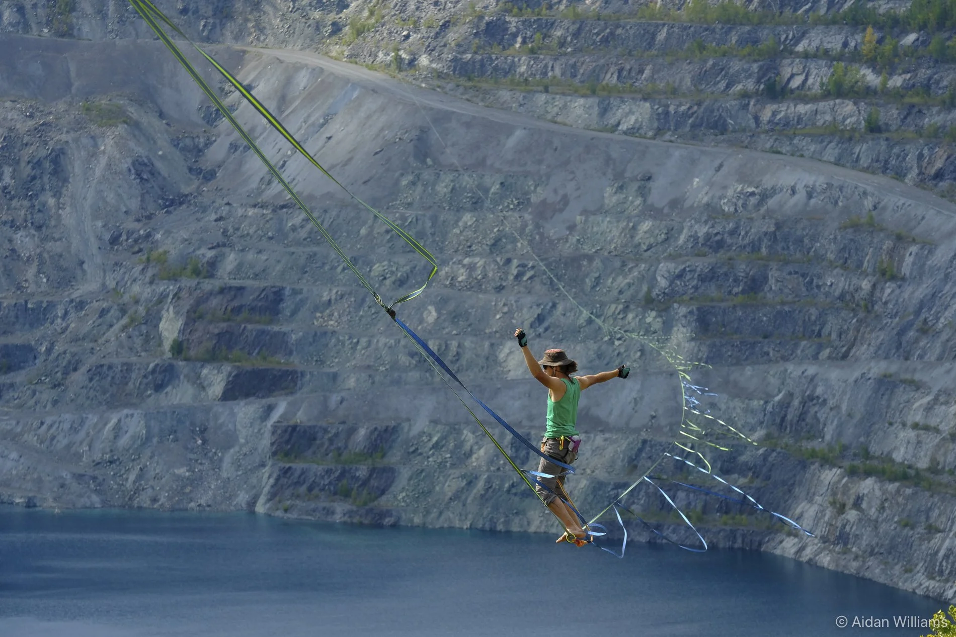 A person kite surfing over a body of water with rocky cliffs in the background.