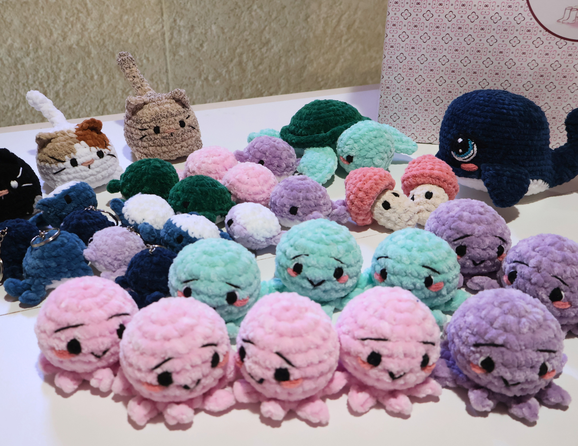 Une collection de peluches en forme de mollusques de différentes tailles et couleurs, avec des visages mignons et de grands yeux, exposées sur une table.