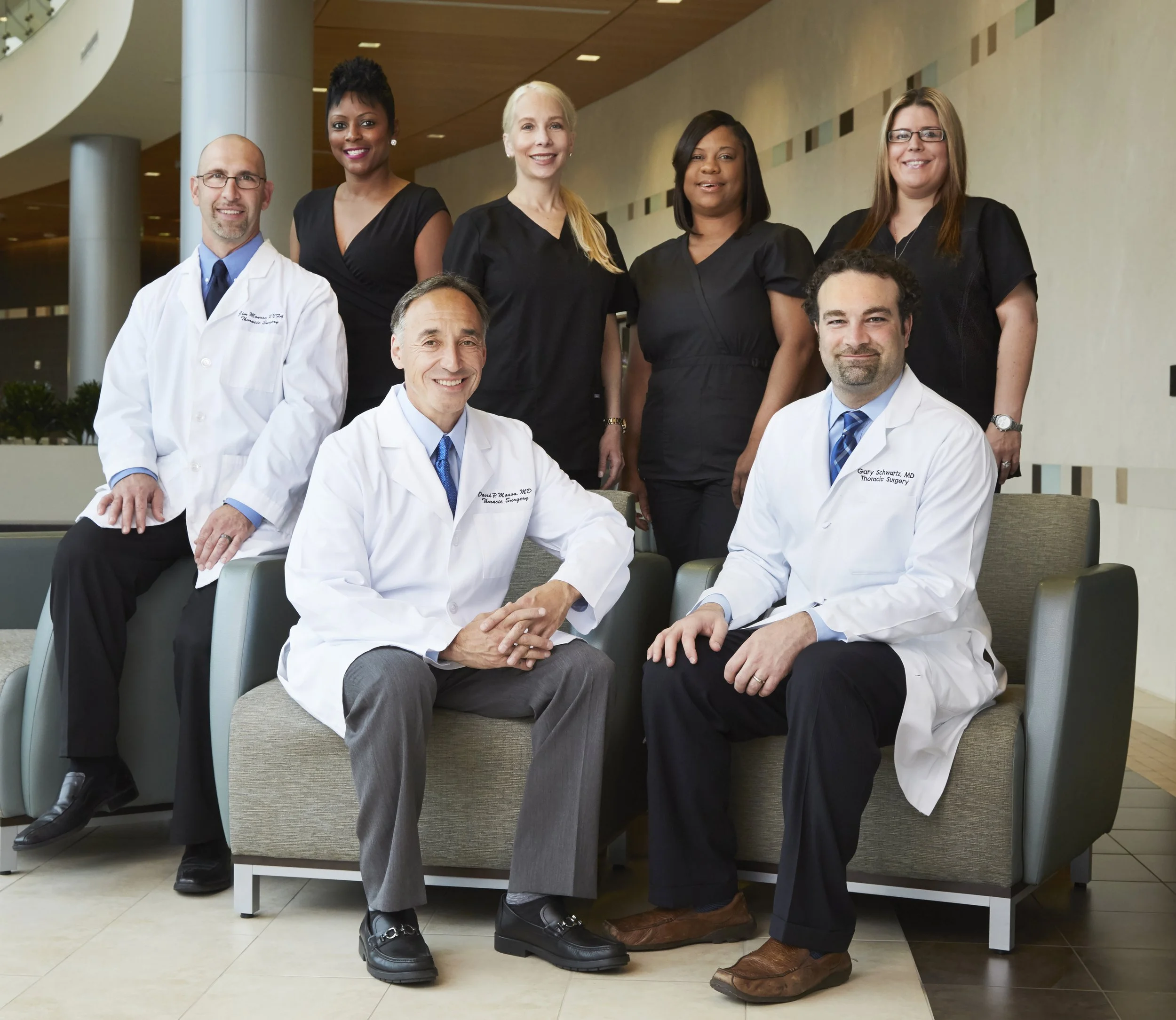A group of medical professionals, including doctors and nurses, posing for a photo in a hospital lobby.
