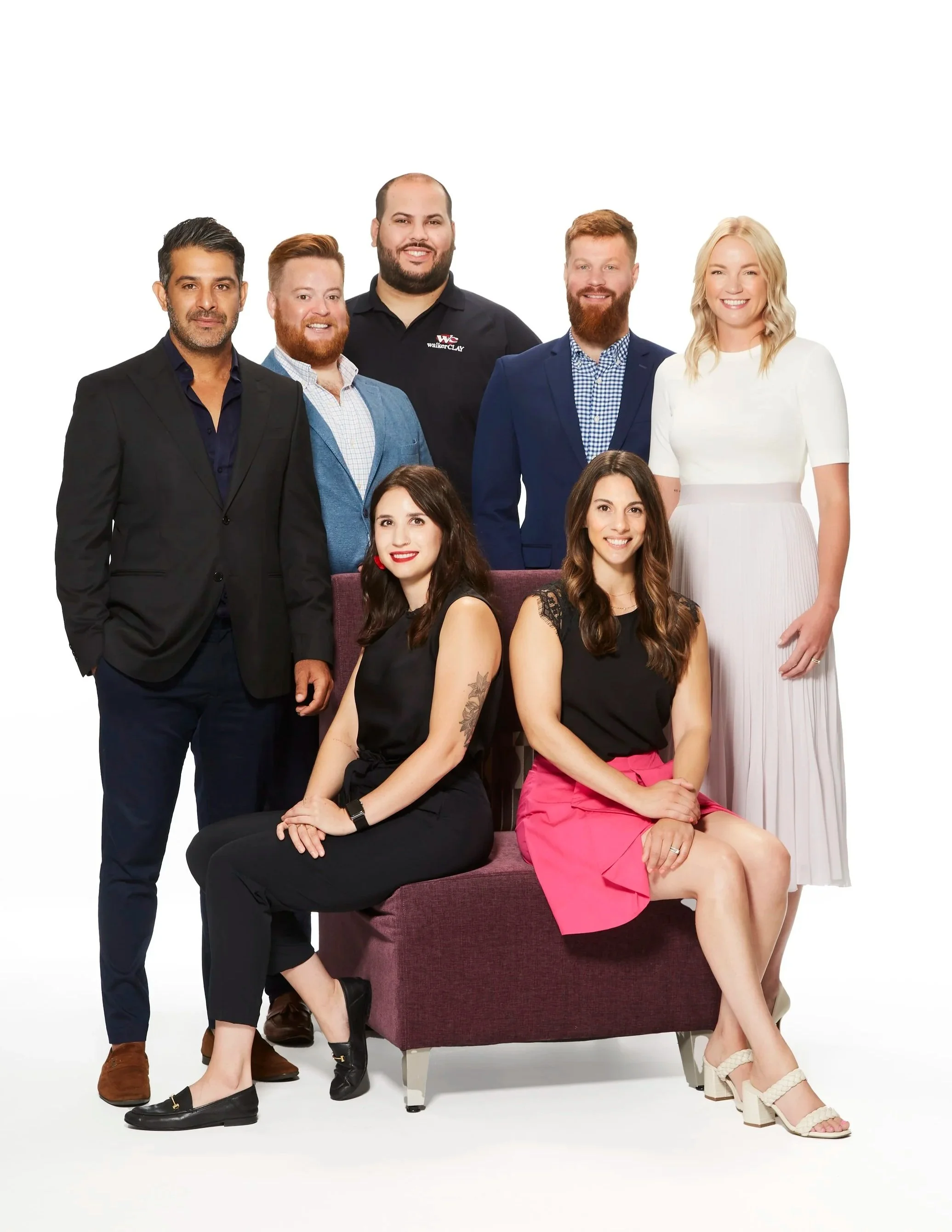 Group of eight diverse professionals posing together against a white background.