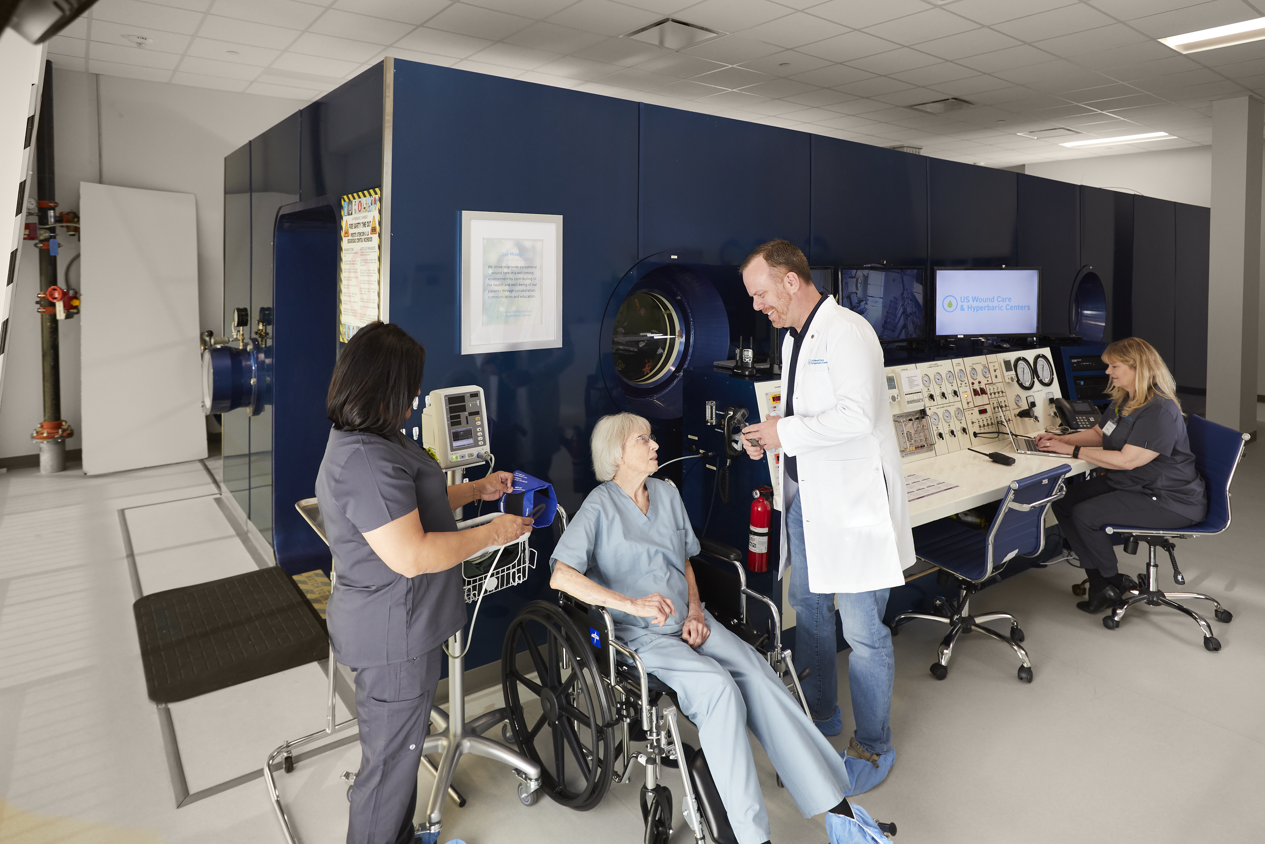 Hospital staff preparing a patient for hyperbaric oxygen therapy in a clinical chamber.
