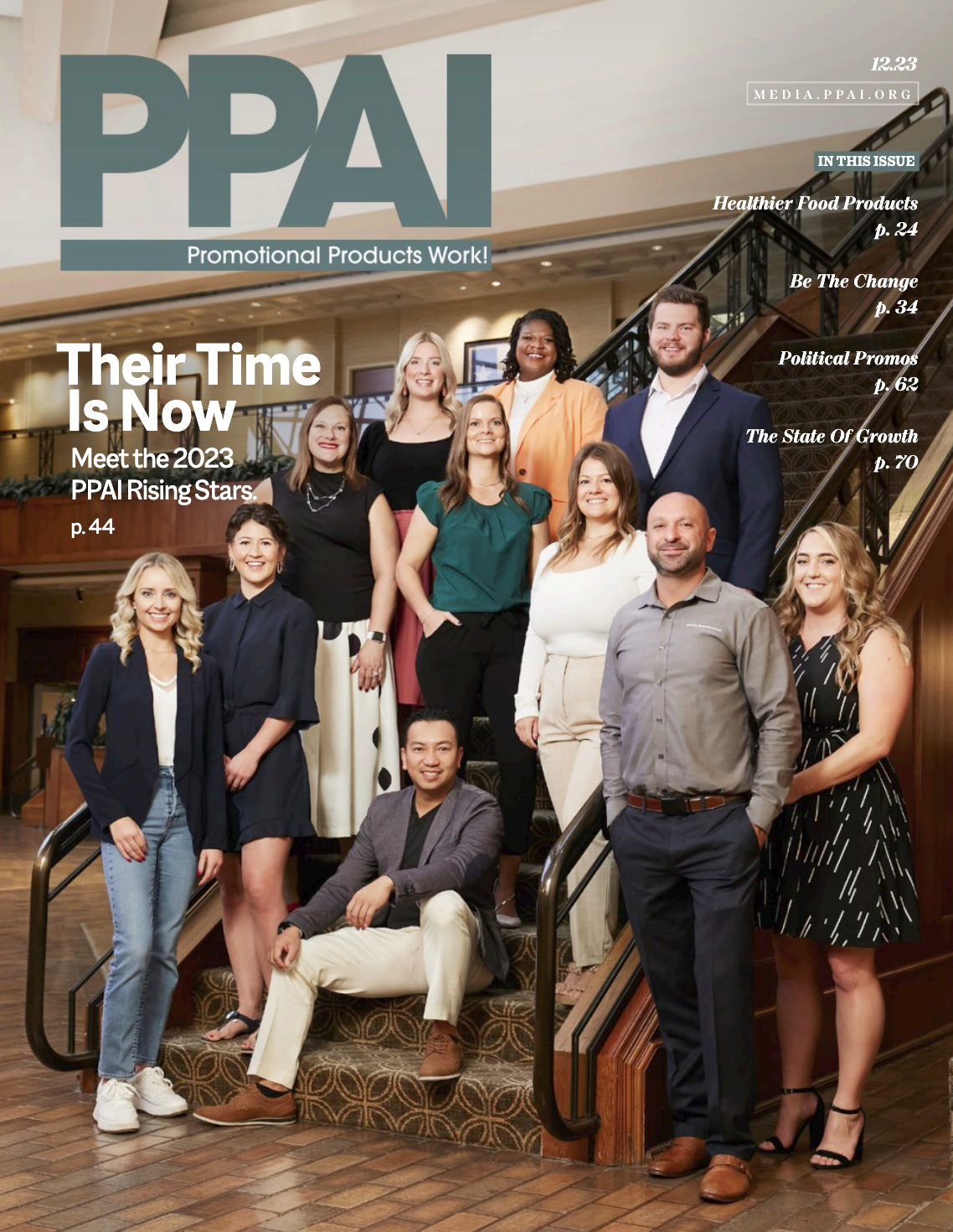 Group of diverse professionals on a staircase in a hotel lobby, posing for a group photo, smiling.