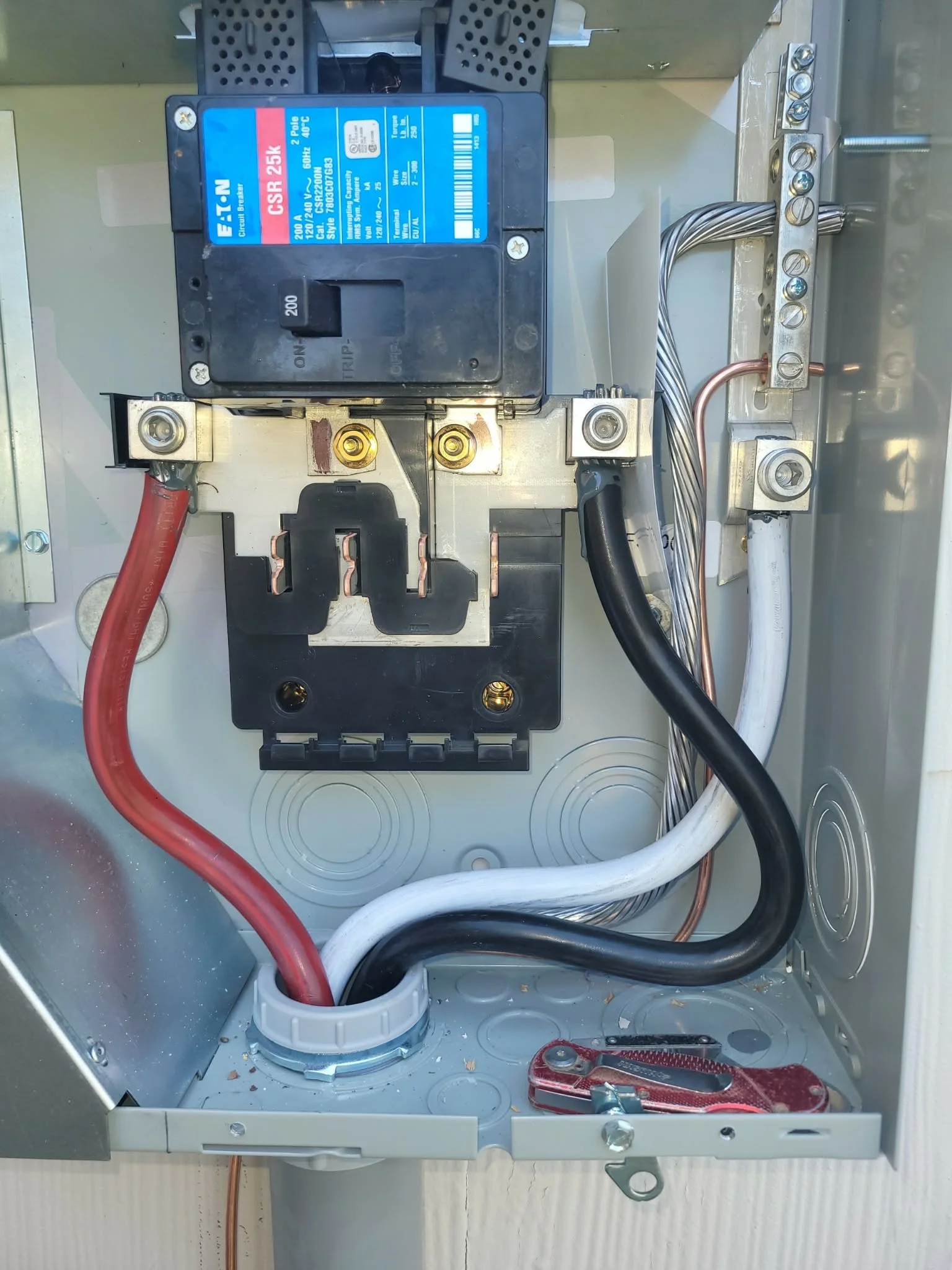 The image shows an electrical control panel with a circuit breaker, several wires, and connectors inside a metal enclosure.