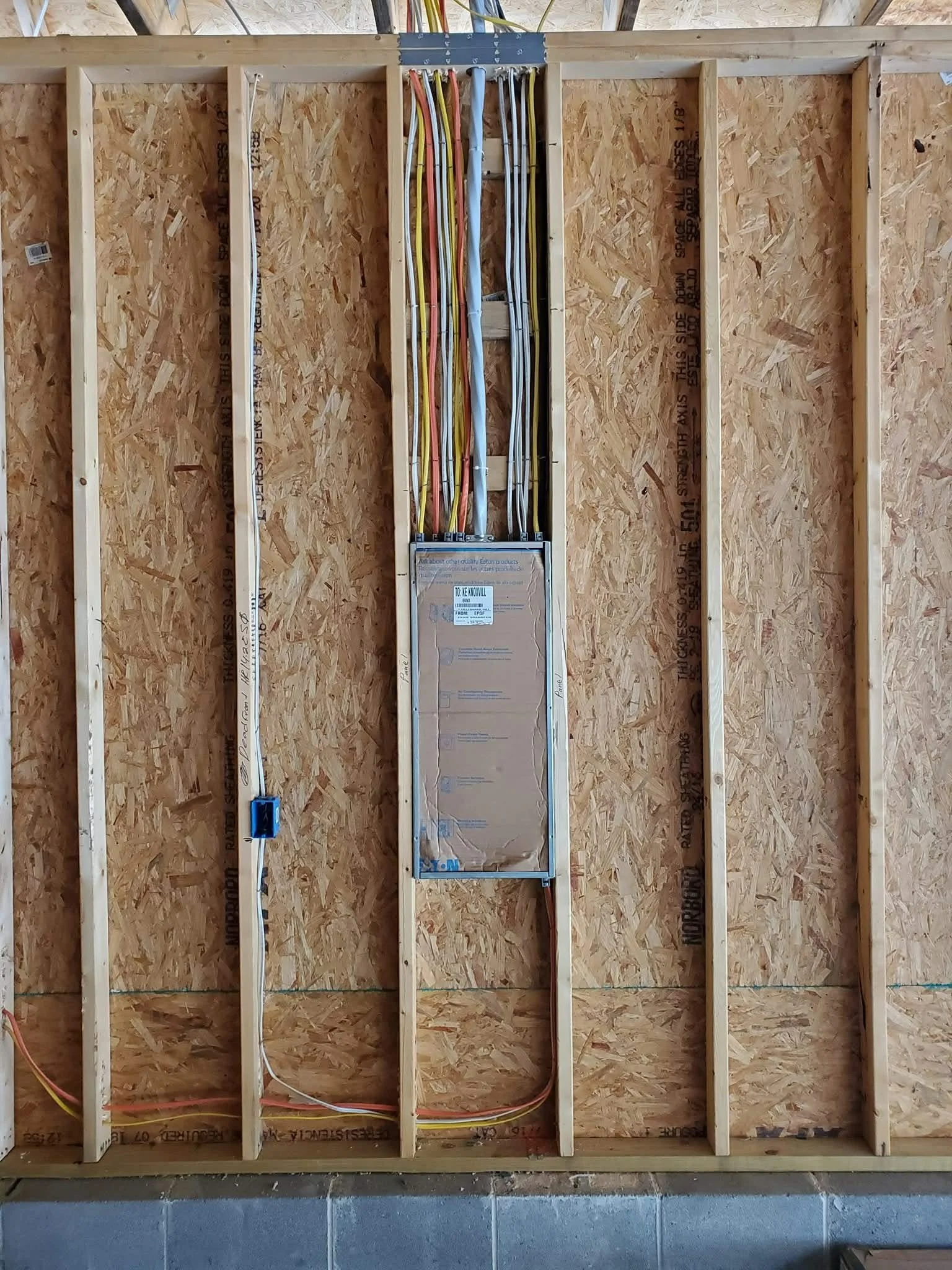 Electrical wiring and box inside a wooden wall frame of a building under construction.