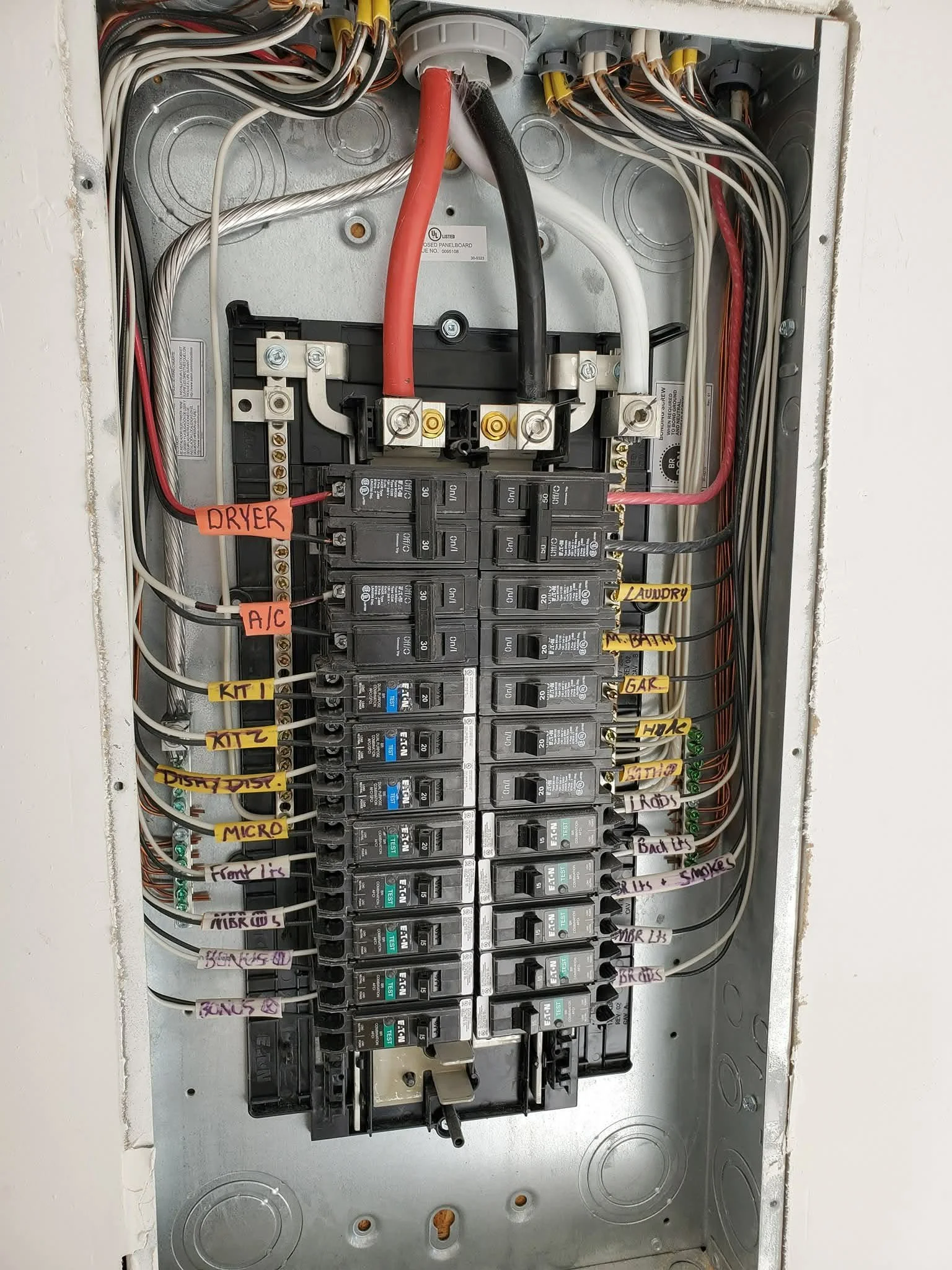 An electrical breaker box with multiple breakers and wires, labeled with categories such as Dryer, A/C, Laundry, Bath, GAF, H/W, and Lights & Smokes.
