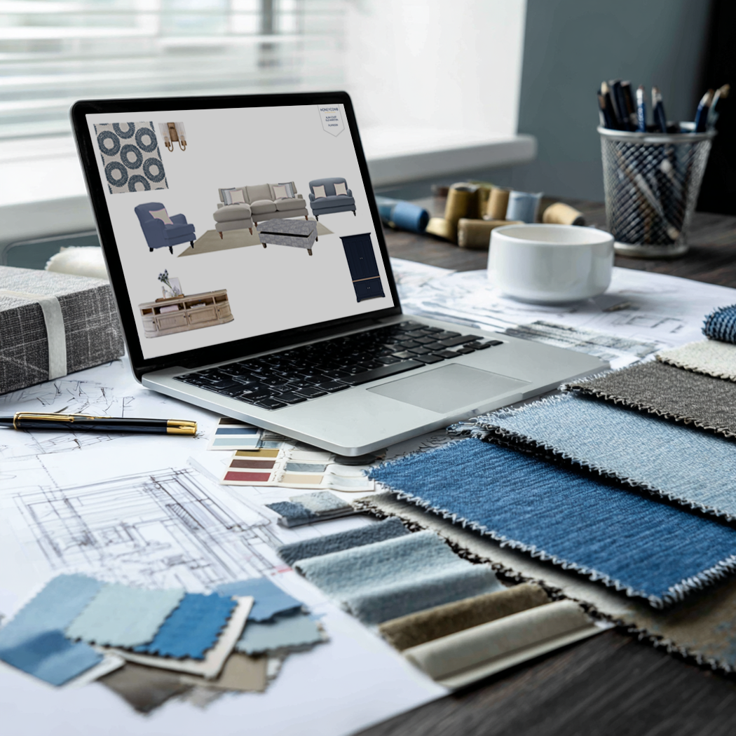 A workspace with fabric swatches, design sketches, and a laptop displaying furniture layout for interior decorating.