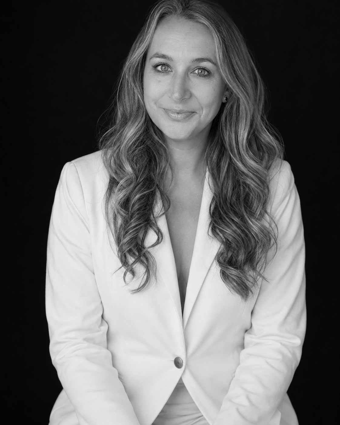 Black-and-white studio portrait of Amy Oughton in a white blazer.