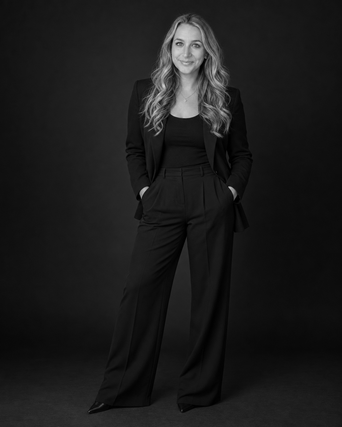 Black-and-white full-length portrait of Amy Oughton in a dark suit.