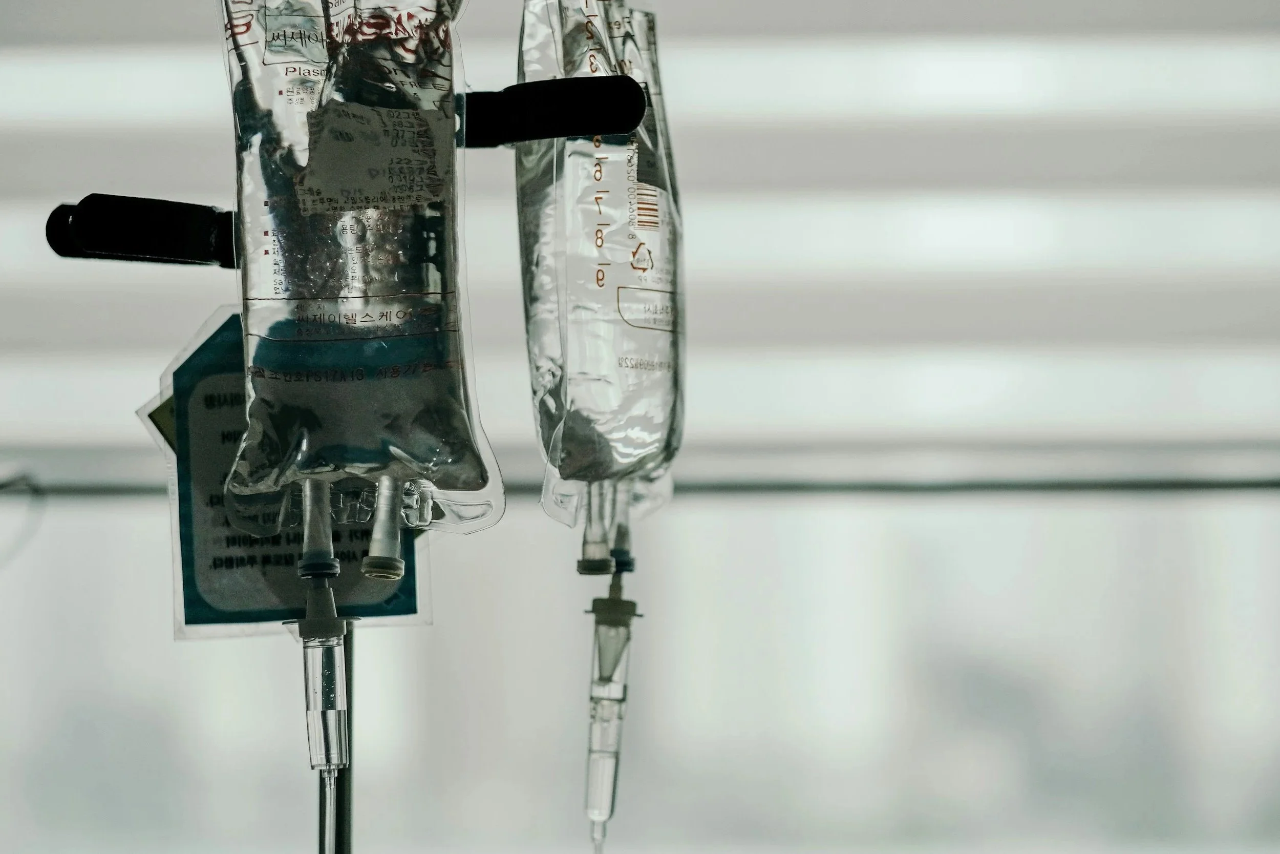 IV drip bags hanging from a stand in a medical setting.