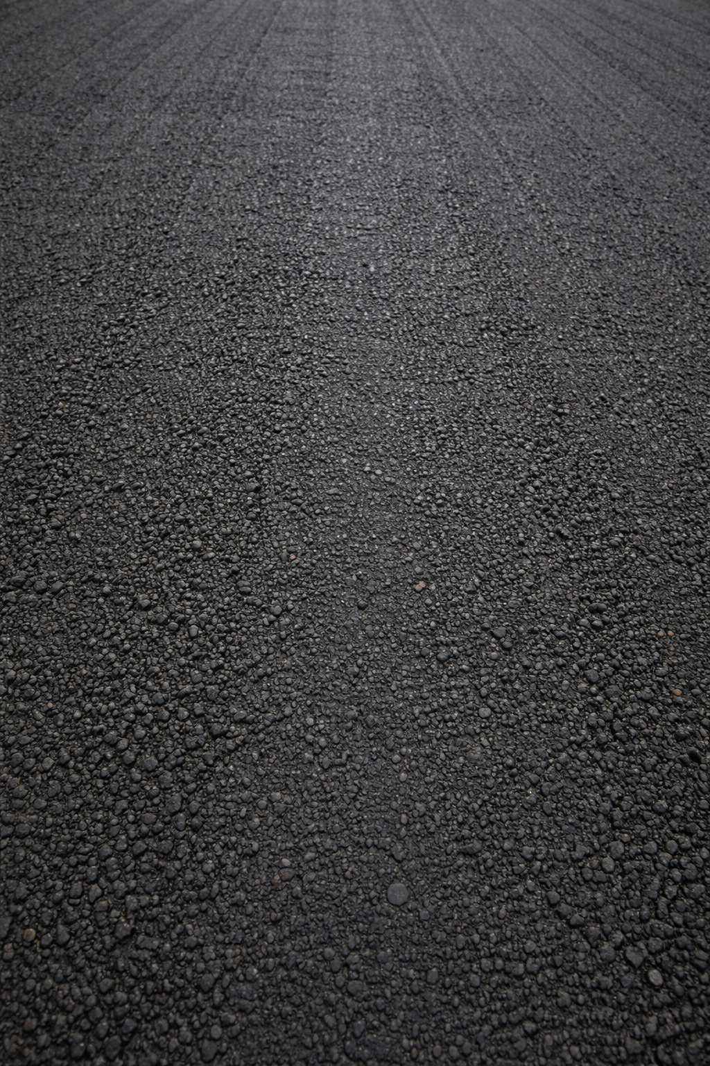 Close-up of asphalt road surface with small gravel stones.