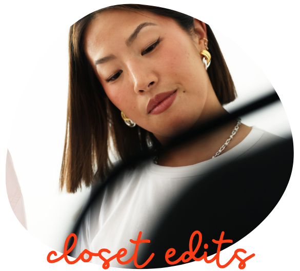 A woman with shoulder-length brown hair, wearing a white top, gold earrings, and a silver necklace, looking down at clothing hangers with red text that says 'closet edit'.