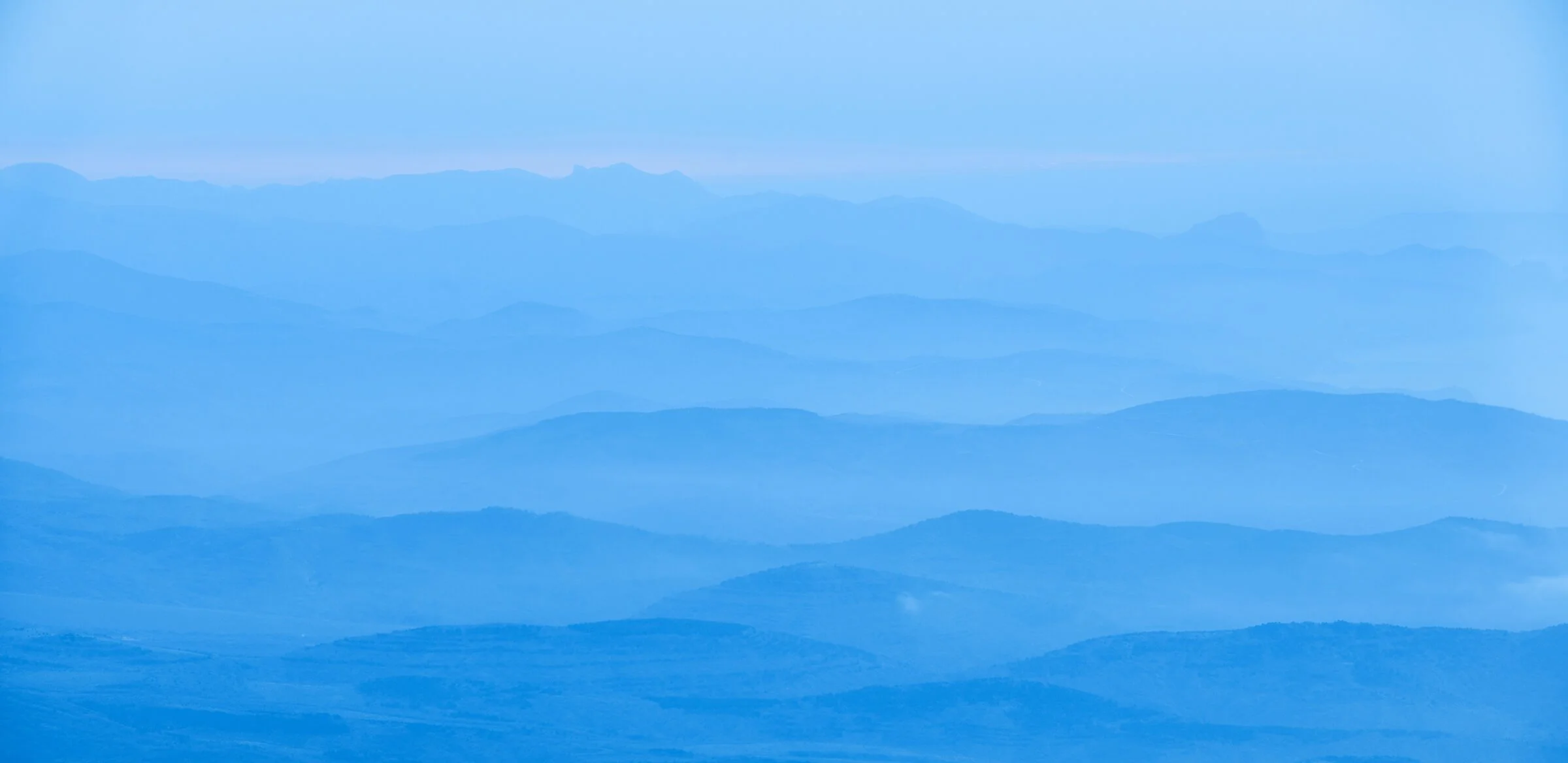 Layered blue mountain ranges fading into the distance under a clear sky.