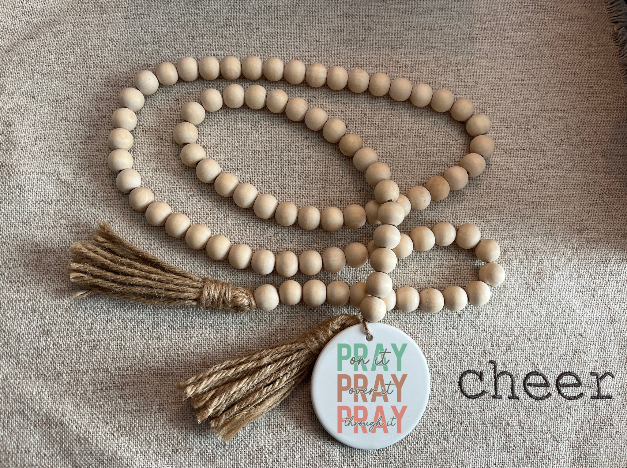 Wooden beaded necklace with tassels and a tag on a textured fabric background