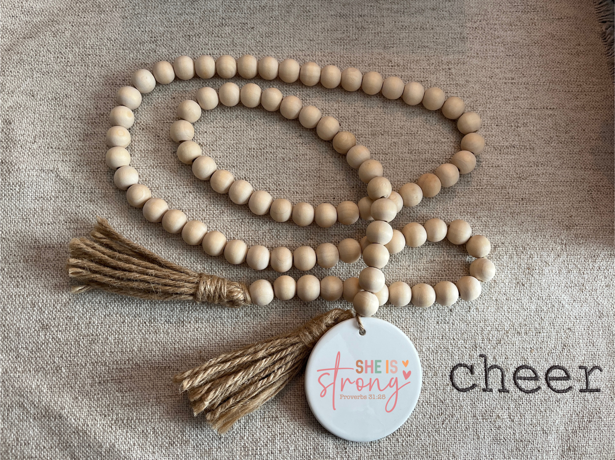 Wooden beaded necklace with tassels and a tag on a textured fabric background
